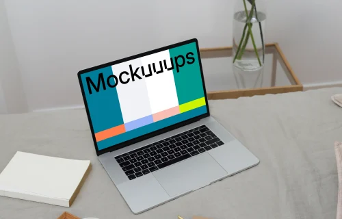 MacBook mockup on a bed with a jug and ceramic on a wooden tray and a notebook at the side