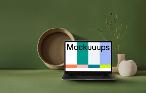 MacBook mockup on a green slab with flower vase at the side