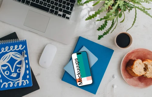 Top view of smartphone mockup next to MacBook and Magic Mouse