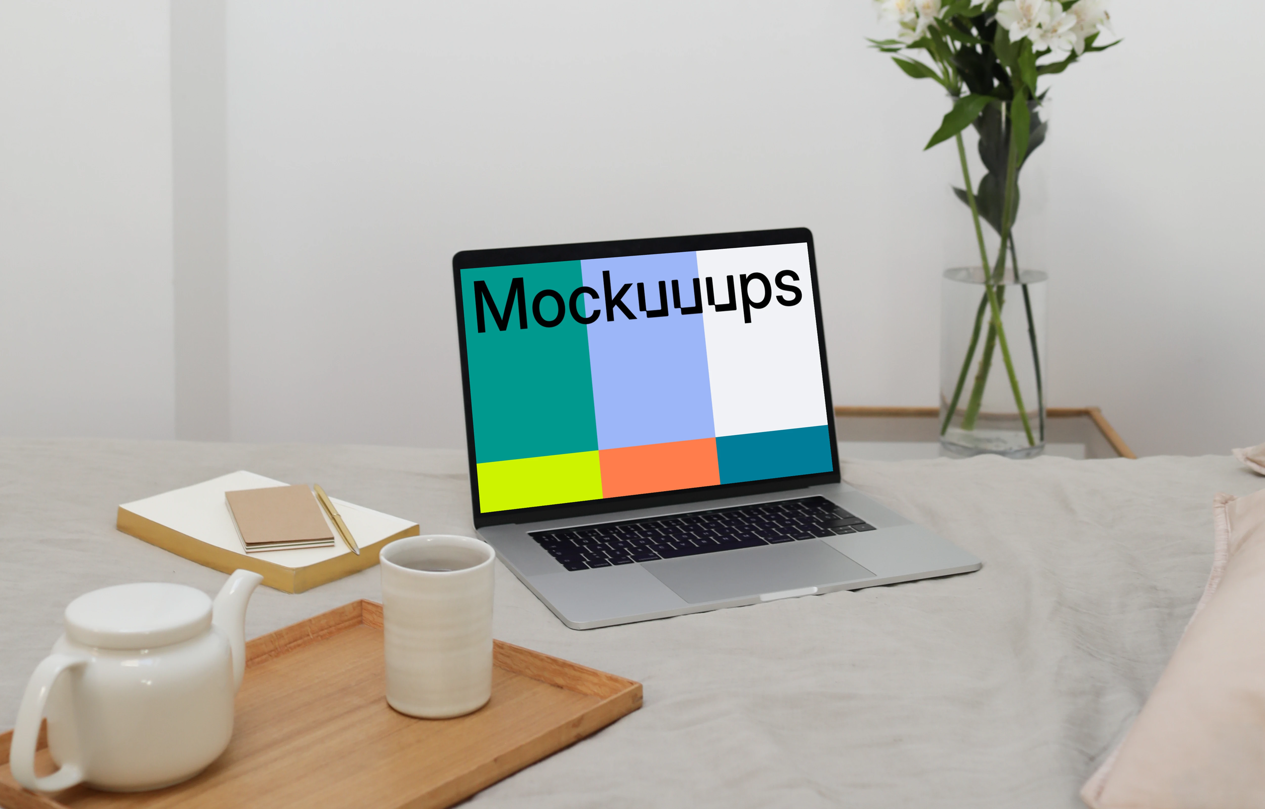 MacBook mockup on a bed with flower vase in the background