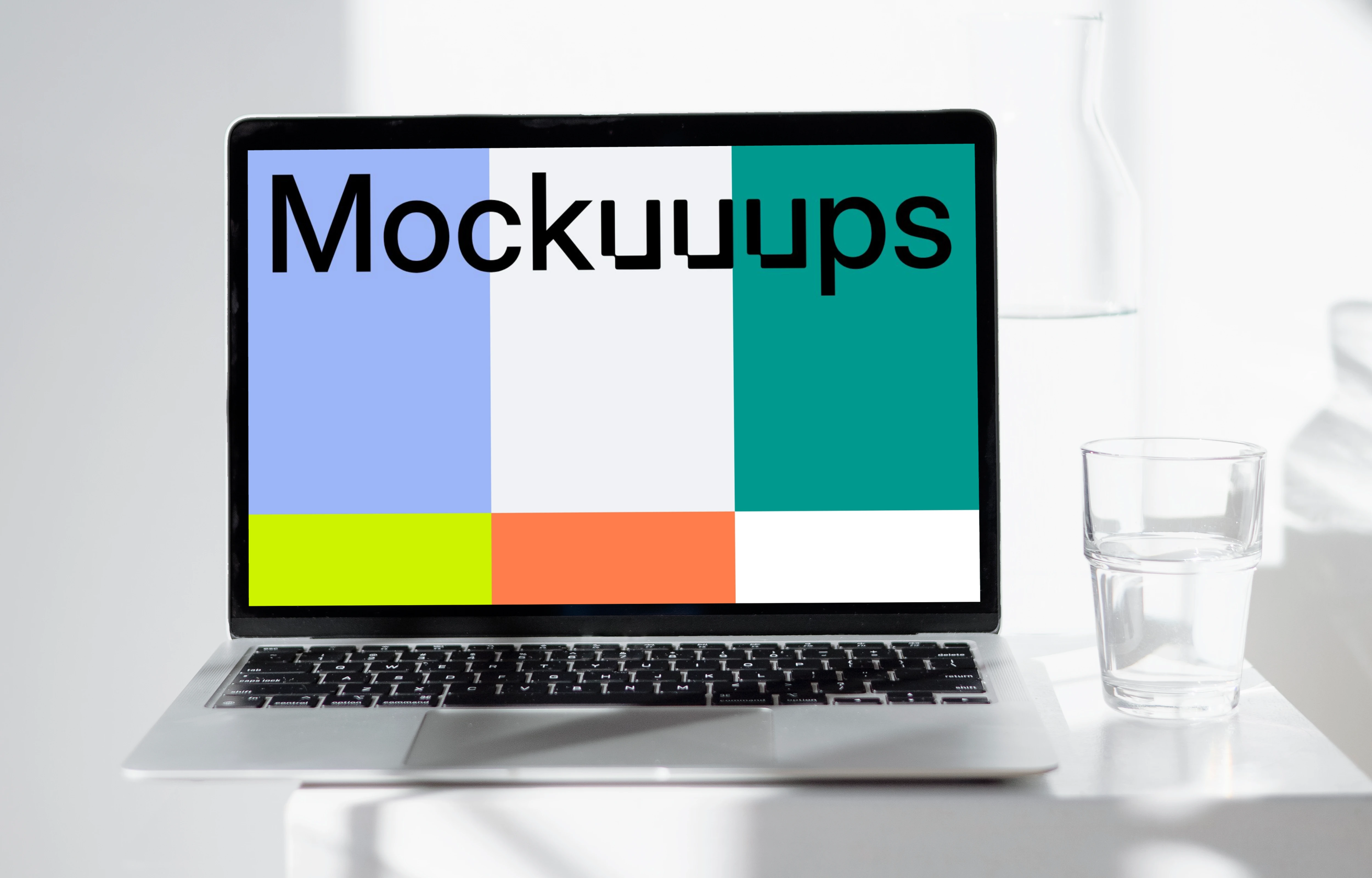 MacBook mockup on a white table with glass of water at the side