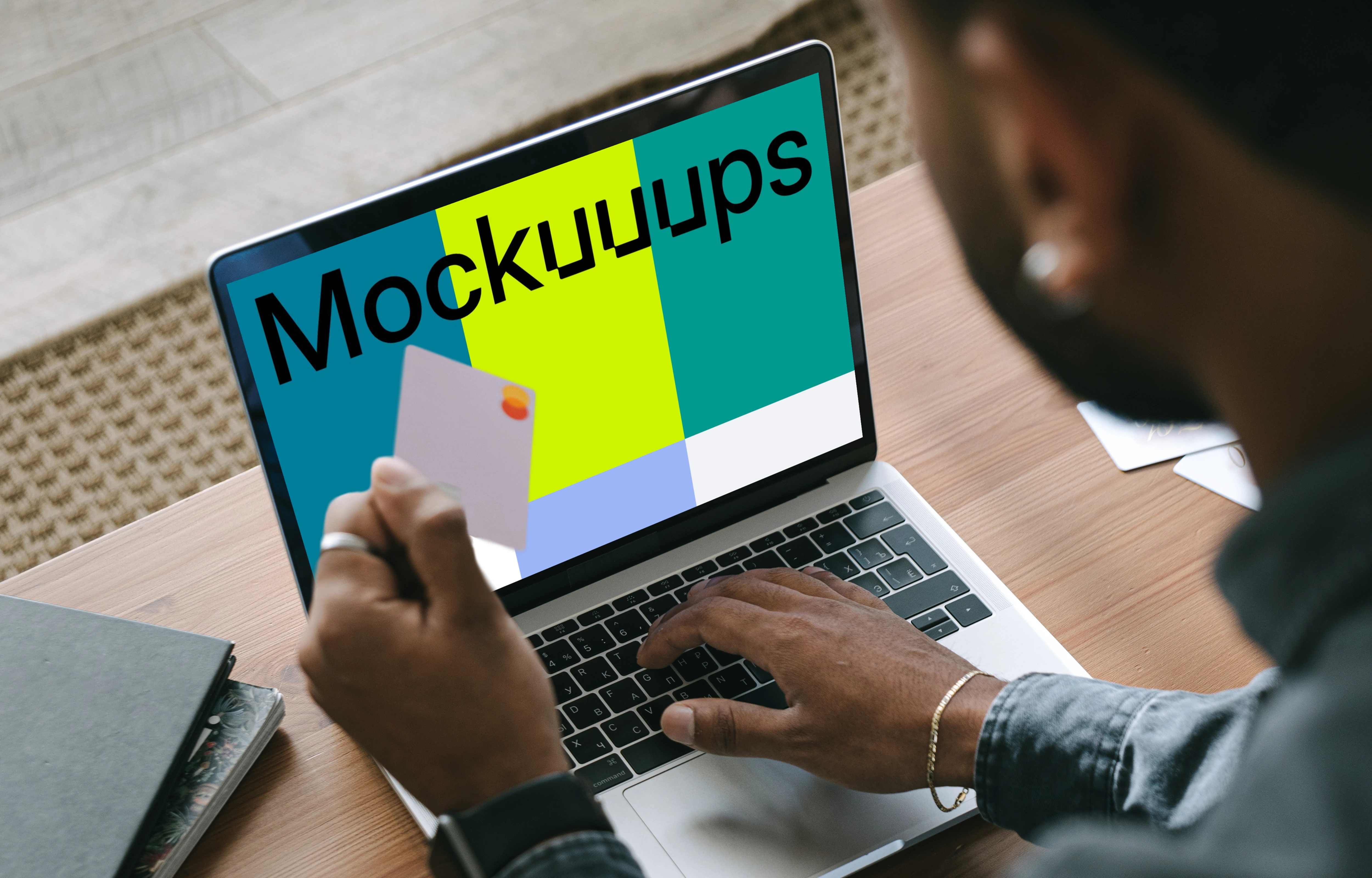 Man in grey shirt shopping mockup paying online with Mastercard on grey MacBook 