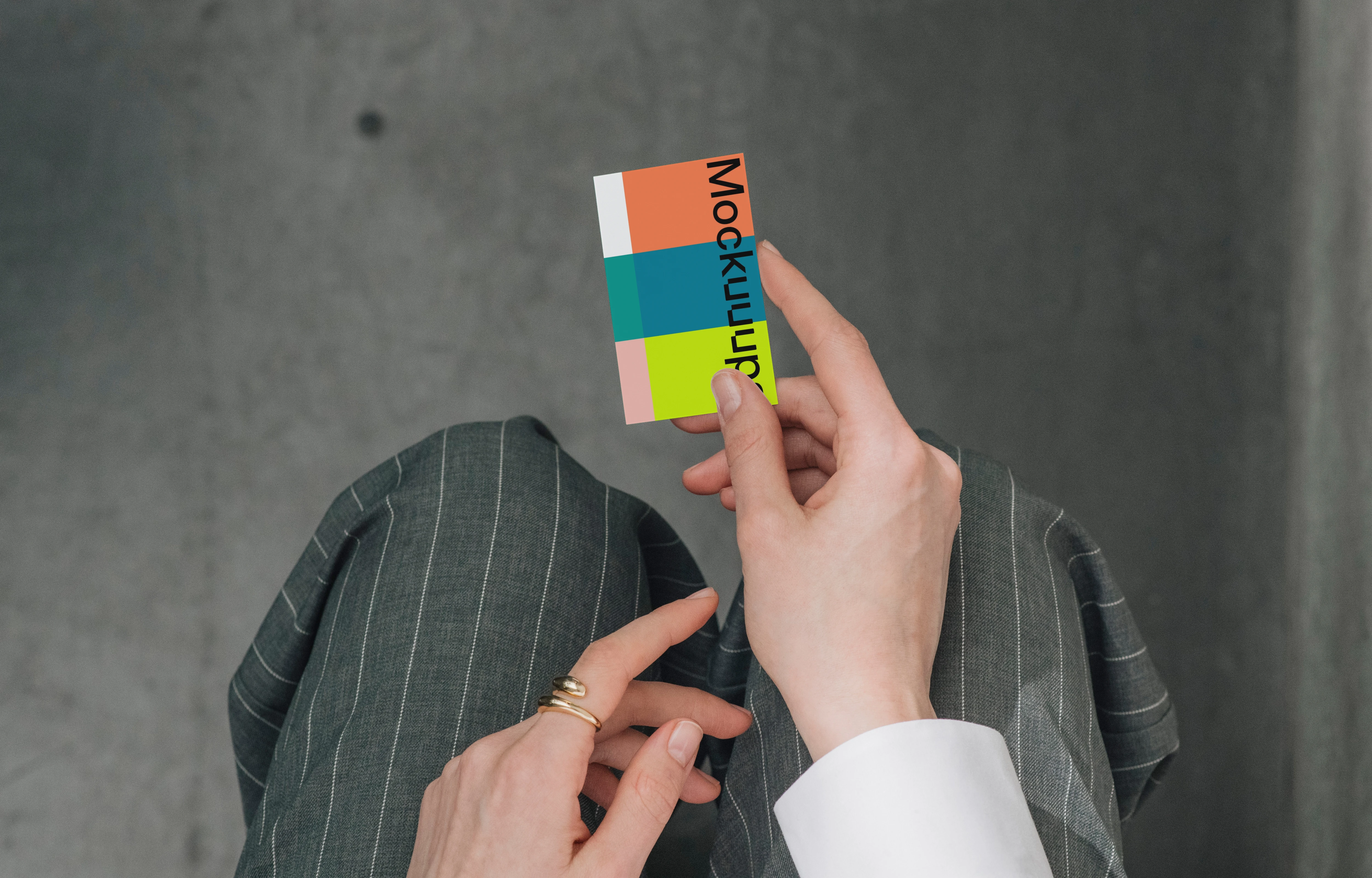 Business card mockup held over a pinstripe suit