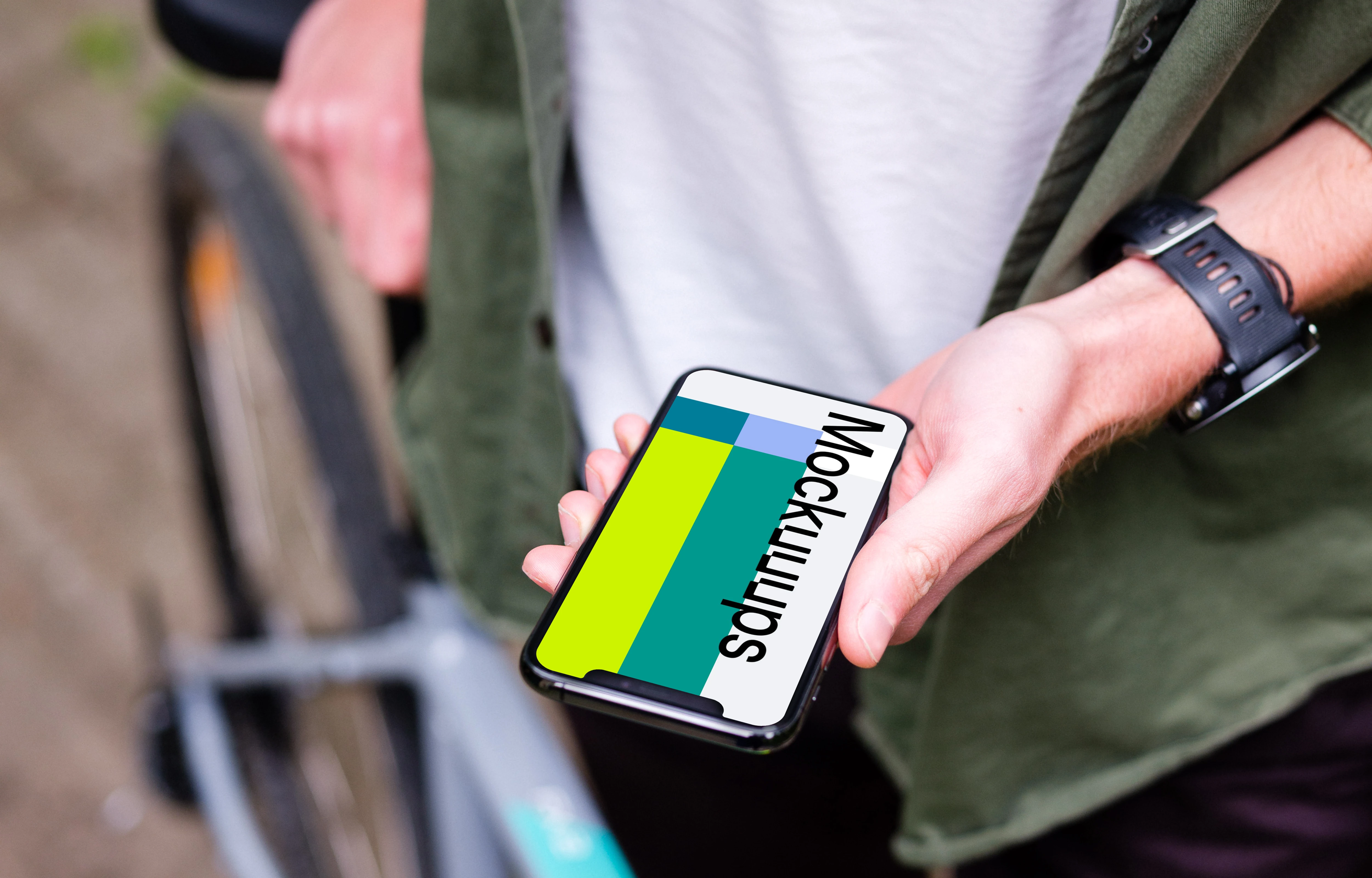 Holding an iPhone 11 Pro mockup whilst stood with a bike