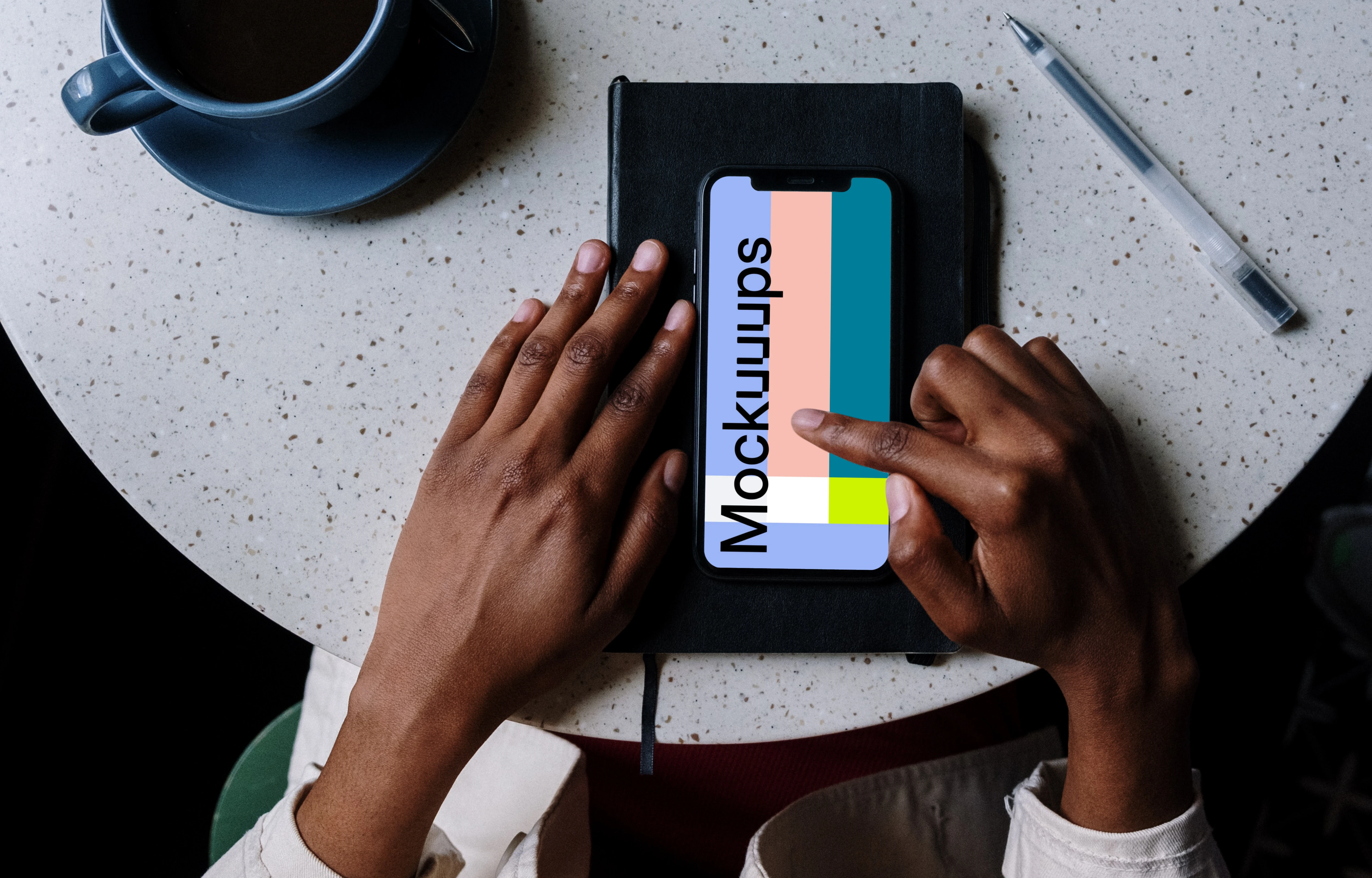 iPhone mockup on black notebook with pen by the side