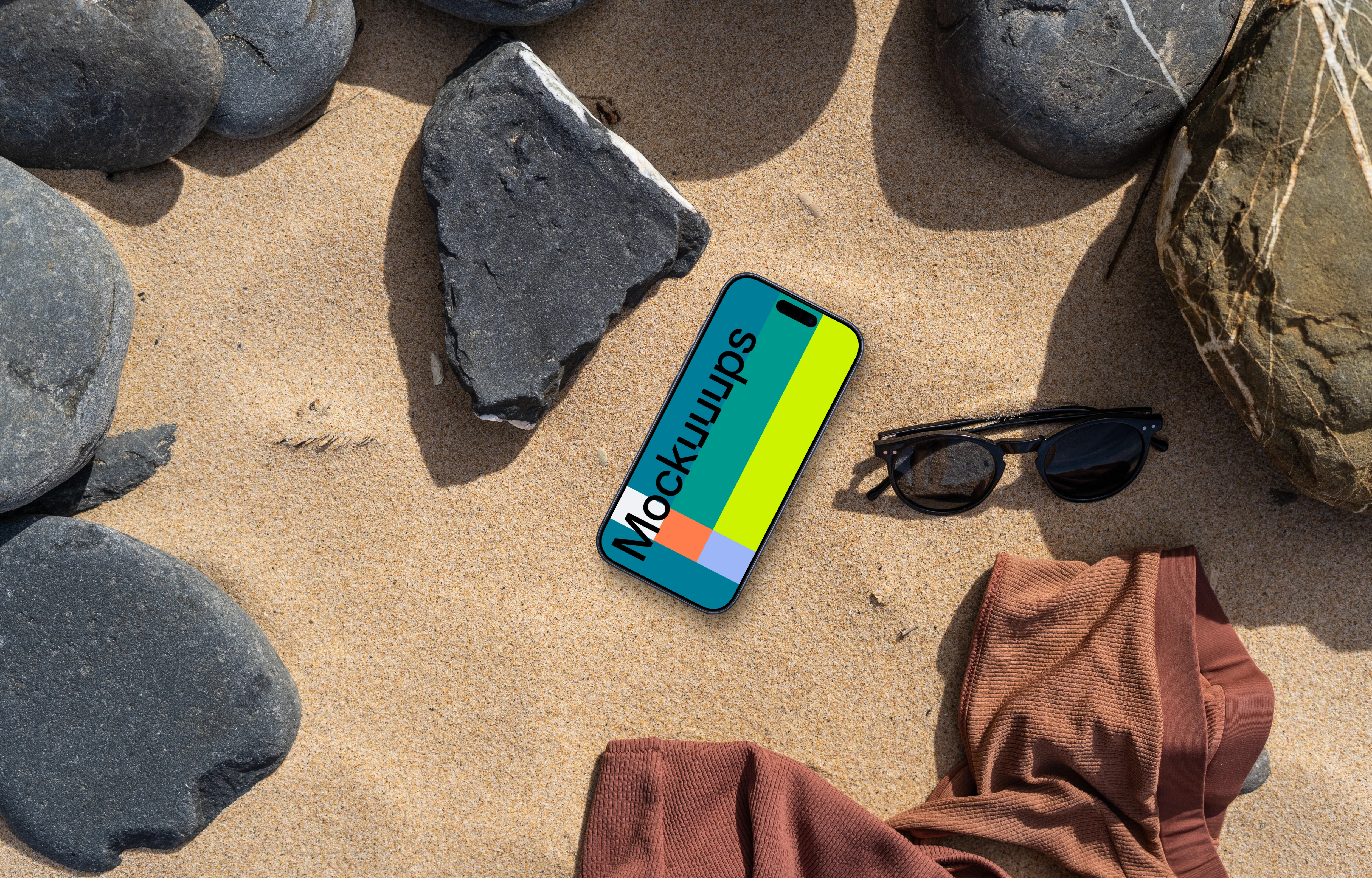 Smartphone mockup on a sandy beach with rocks