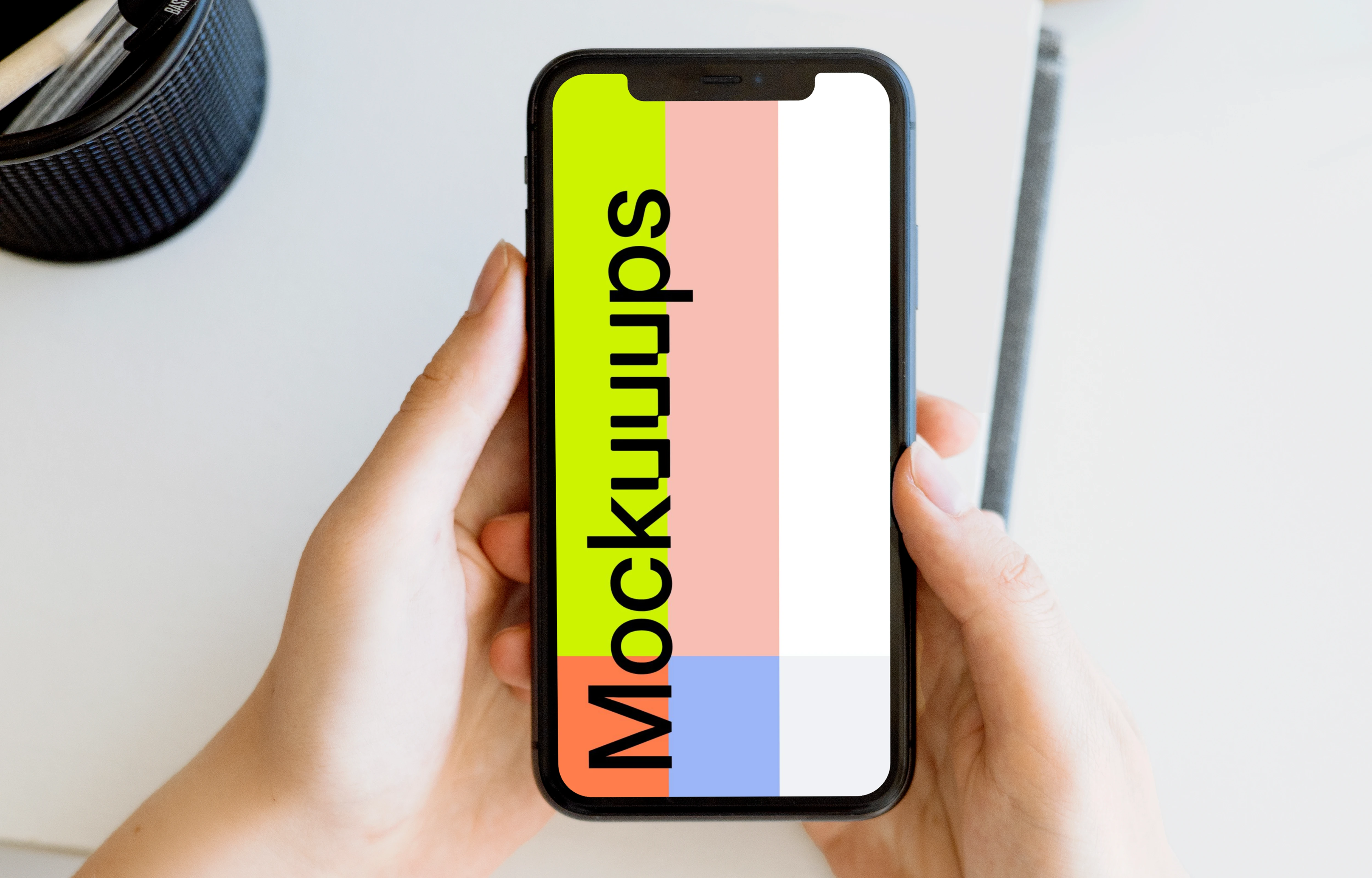 iPhone mockup held with two hands by a user above a white table