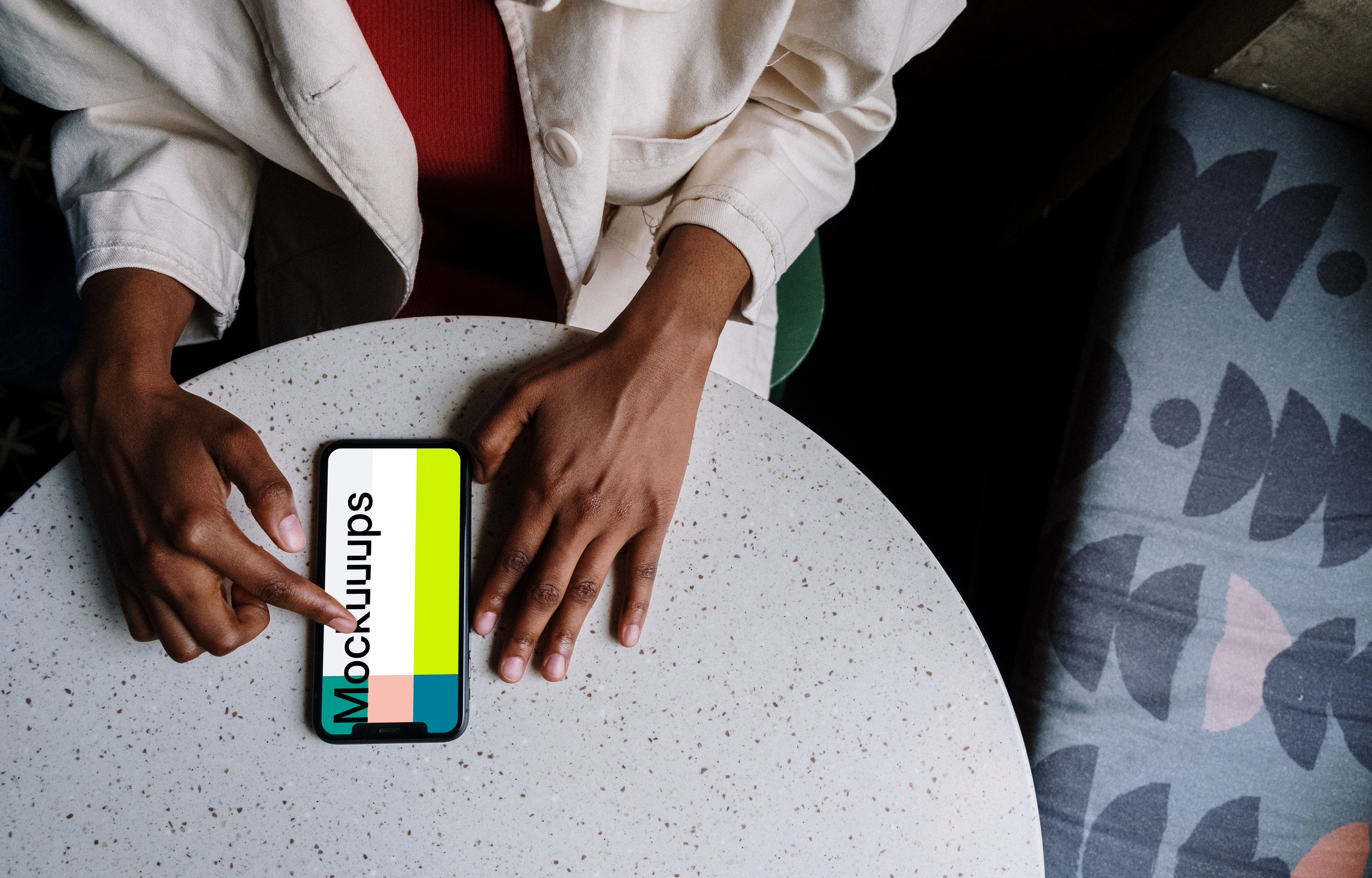 iPhone mockup on white table and a bed by the side