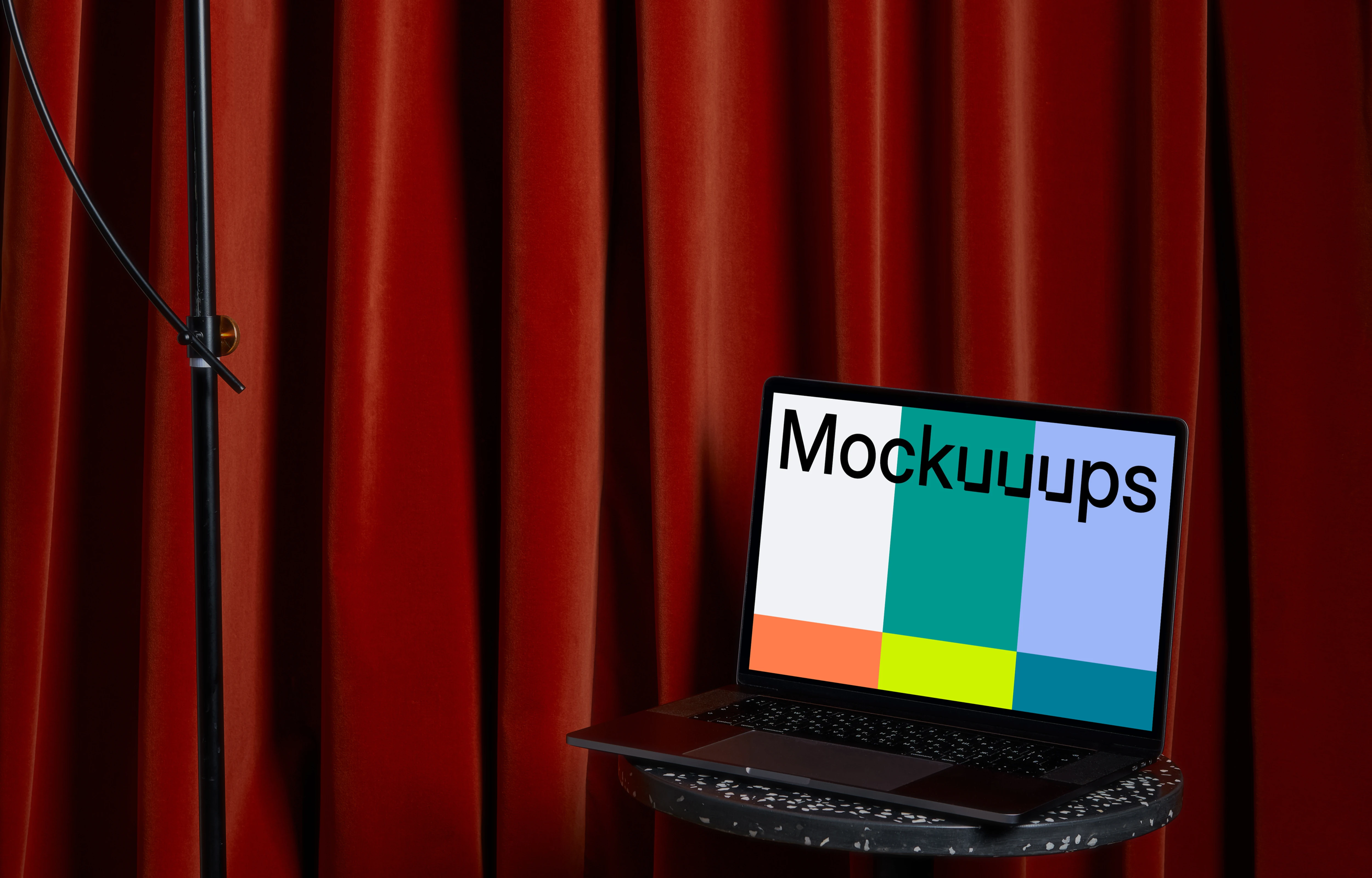 MacBook mockup on a black stool with a tall lamp hanging above it