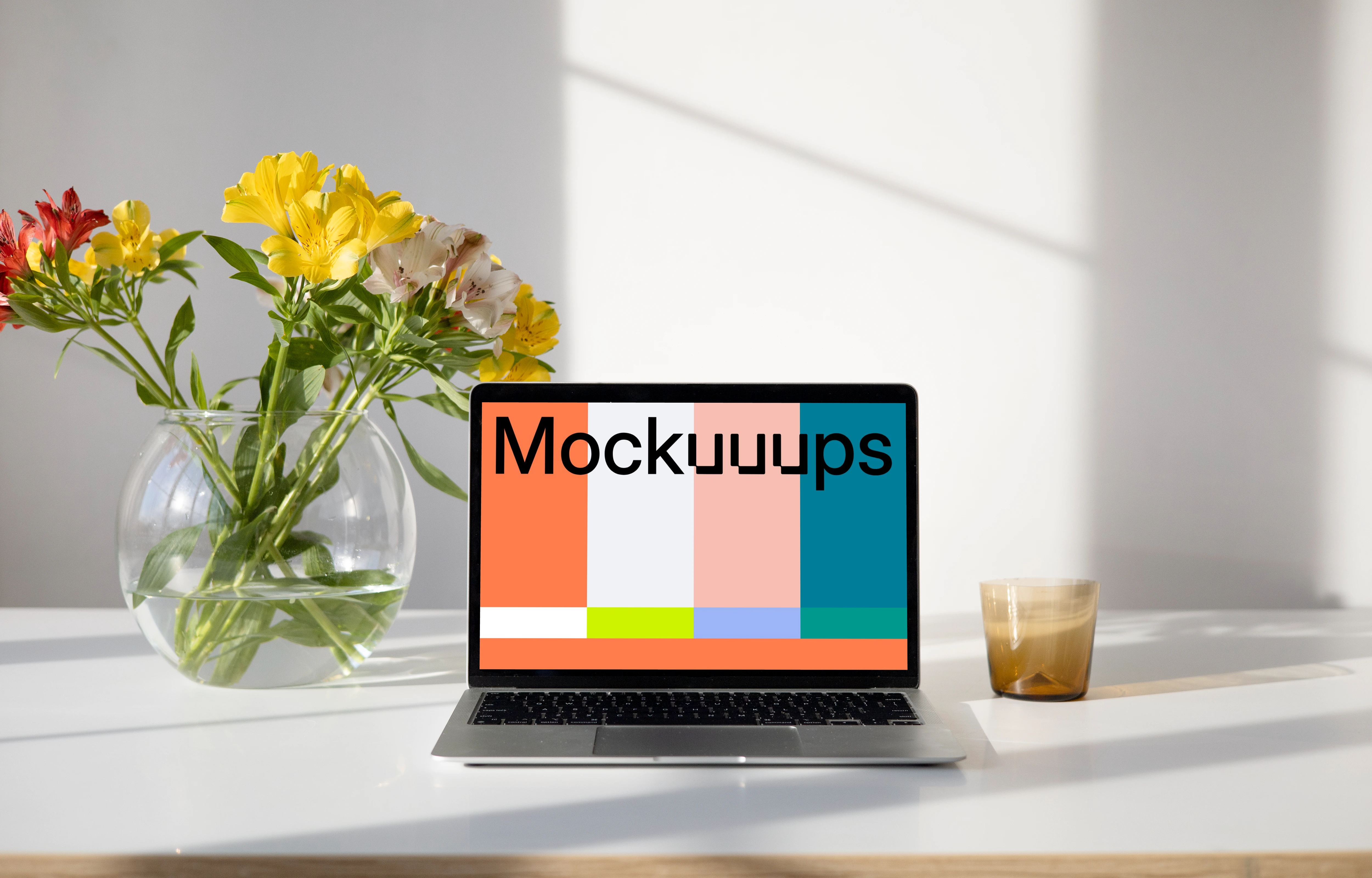 MacBook mockup on a table with flower vase containing water and beautiful flowers