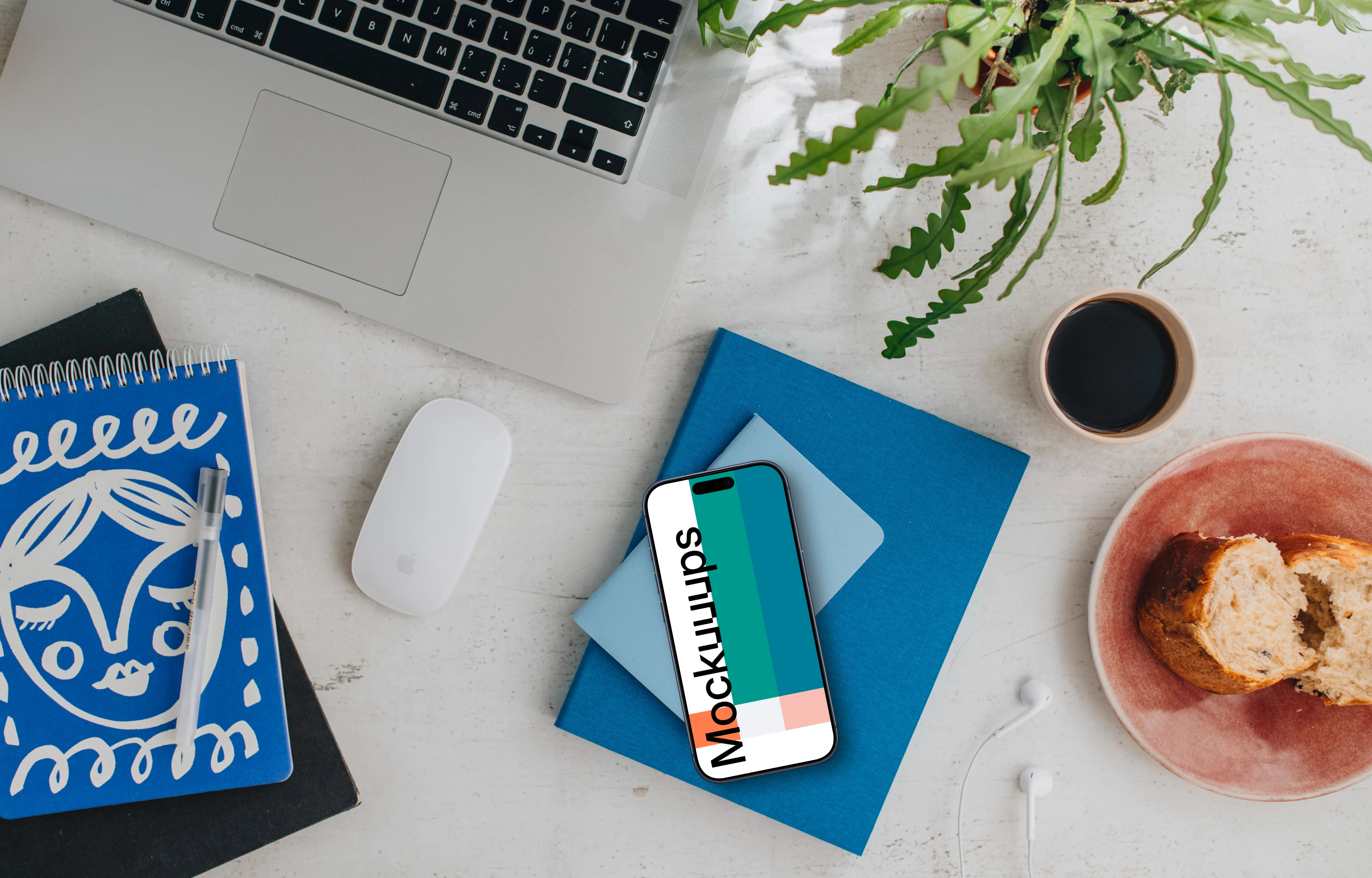 Top view of smartphone mockup next to MacBook and Magic Mouse