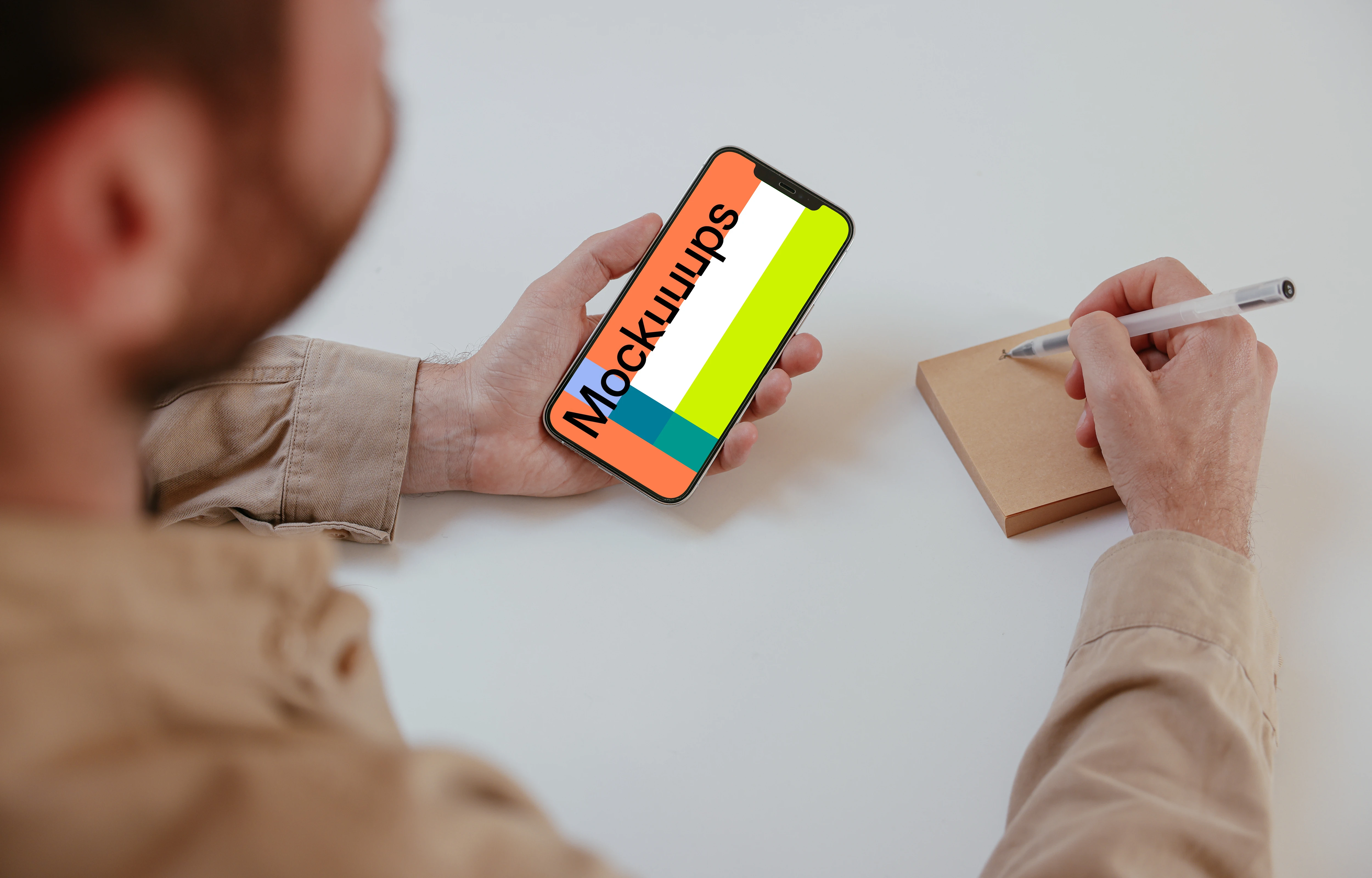 User holding an iPhone and writing into a sticky note mockup
