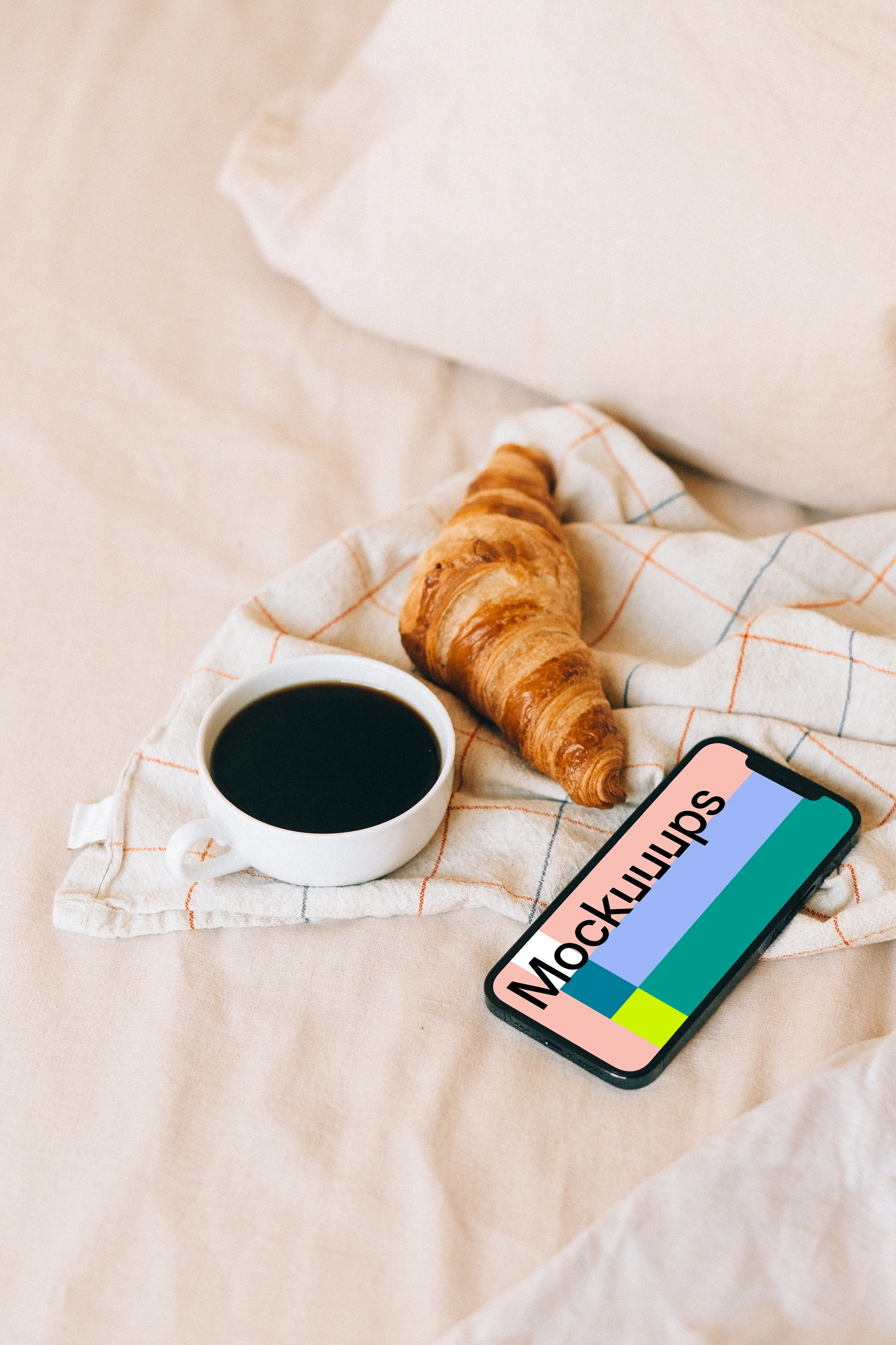 iPhone 12 Pro mockup beside a croissant and a cup of coffee
