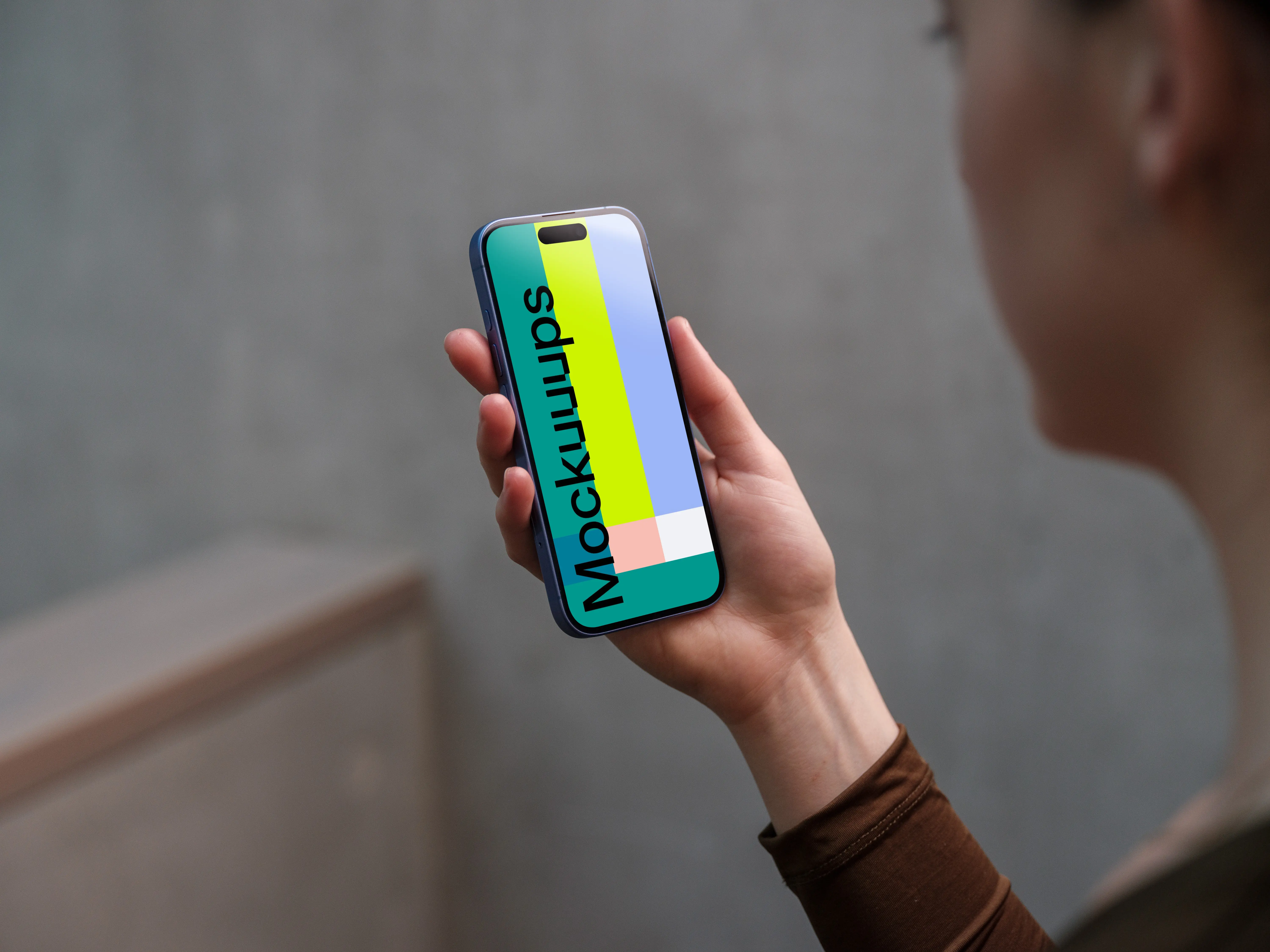 iPhone 16 mockup in a woman's hand with concrete backdrop