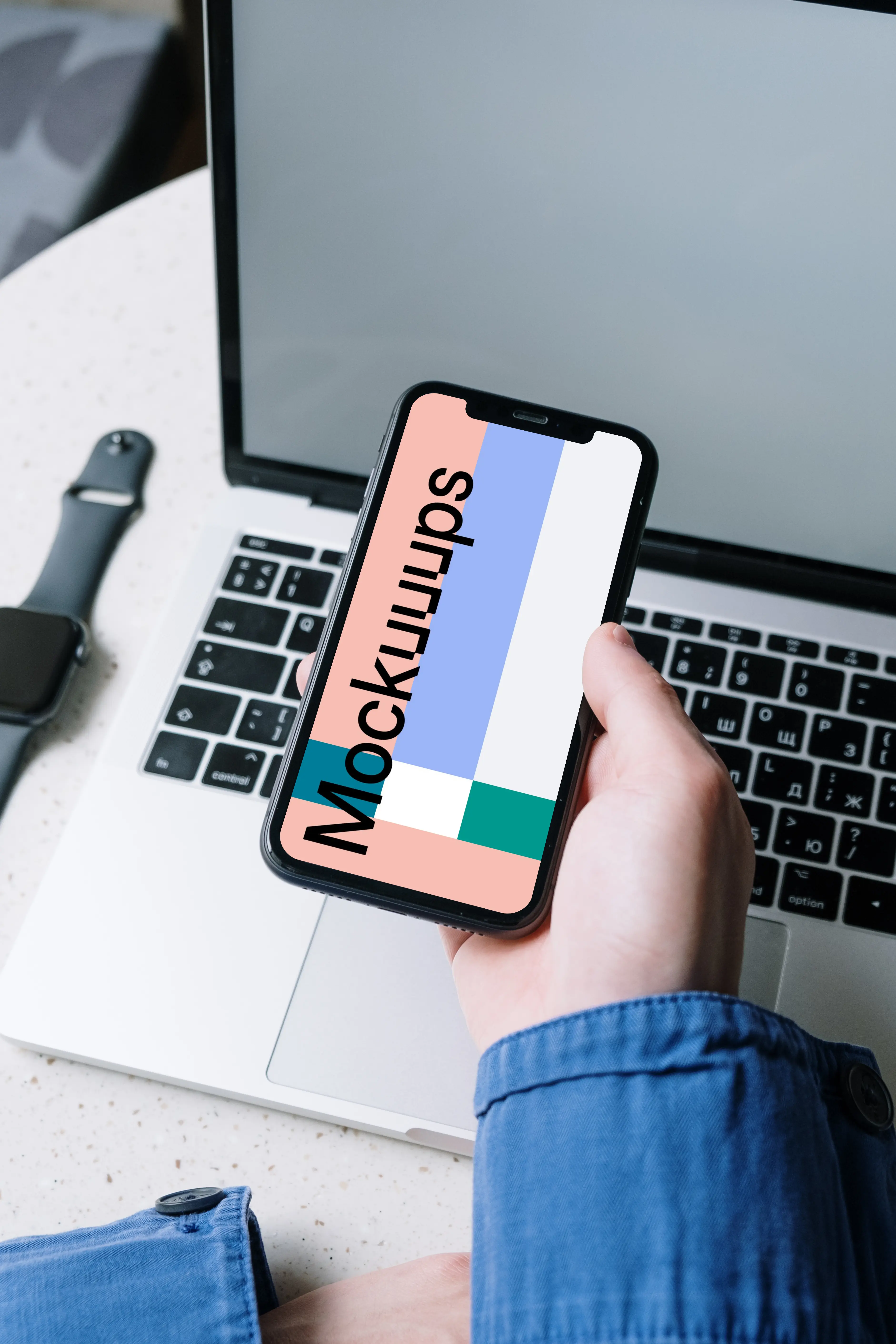 iPhone mockup held above a MacBook by a user in corporate dressing