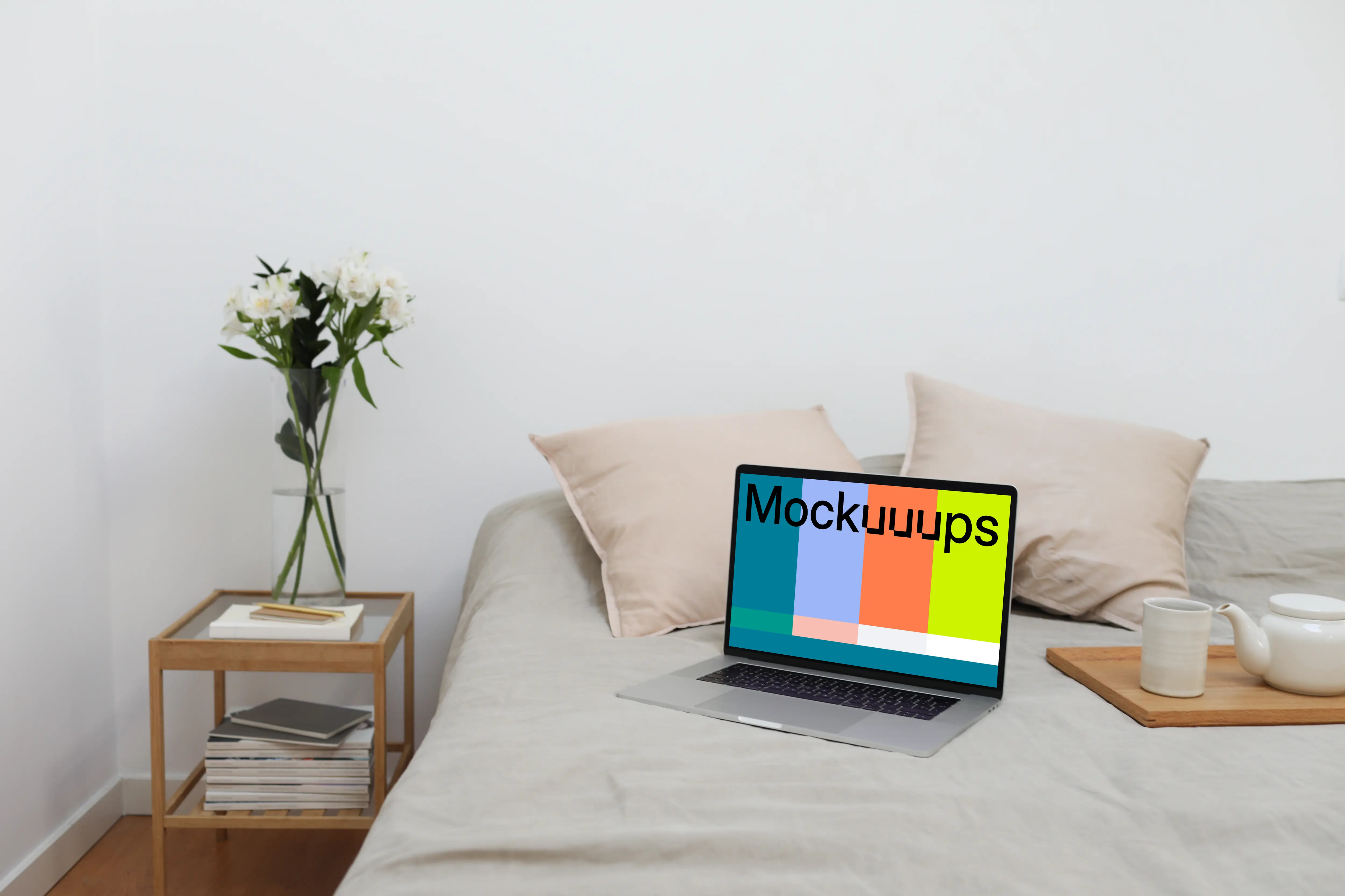 MacBook mockup on a bed with tea set by the side