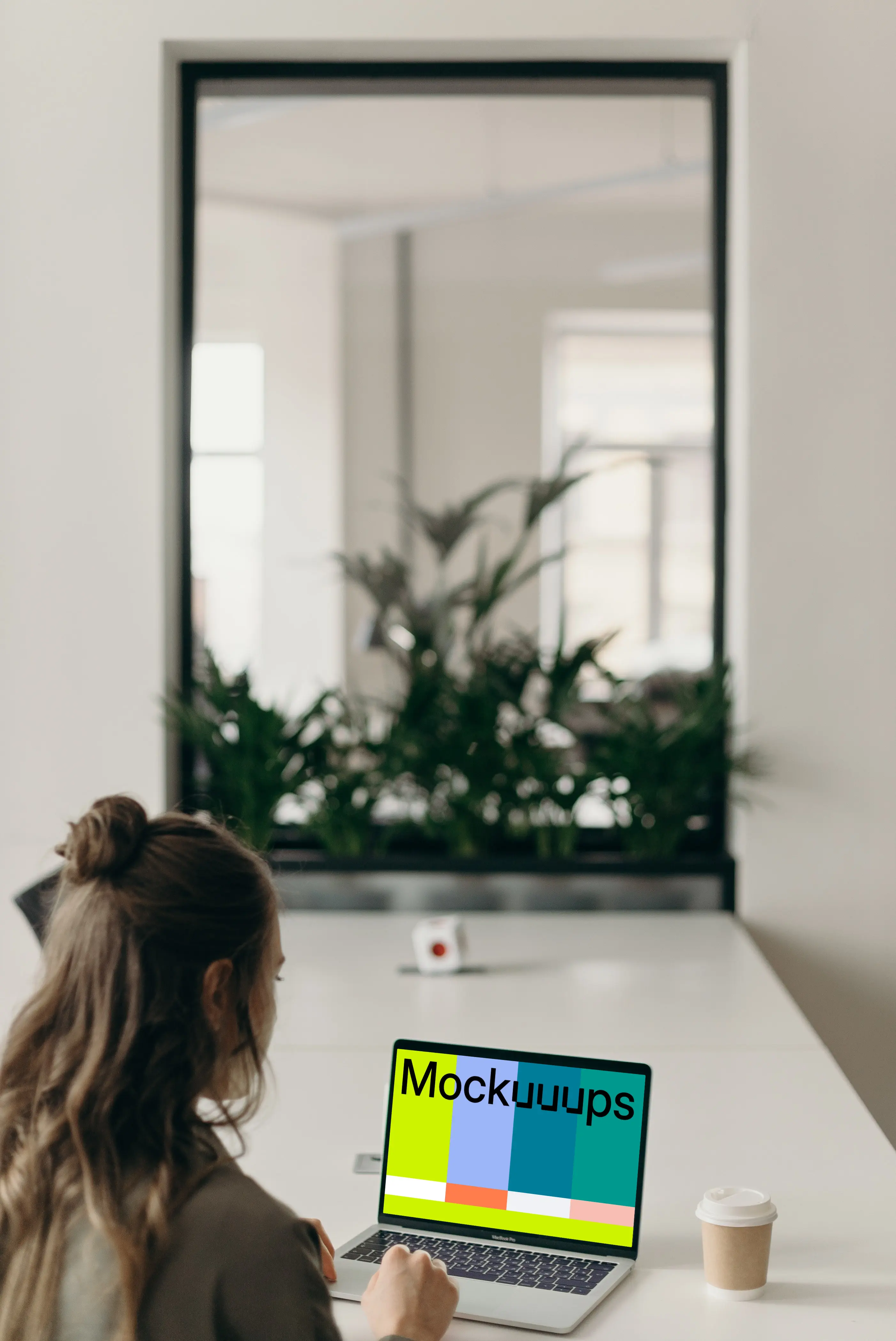 MacBook Pro mockup on a white table in use by a woman