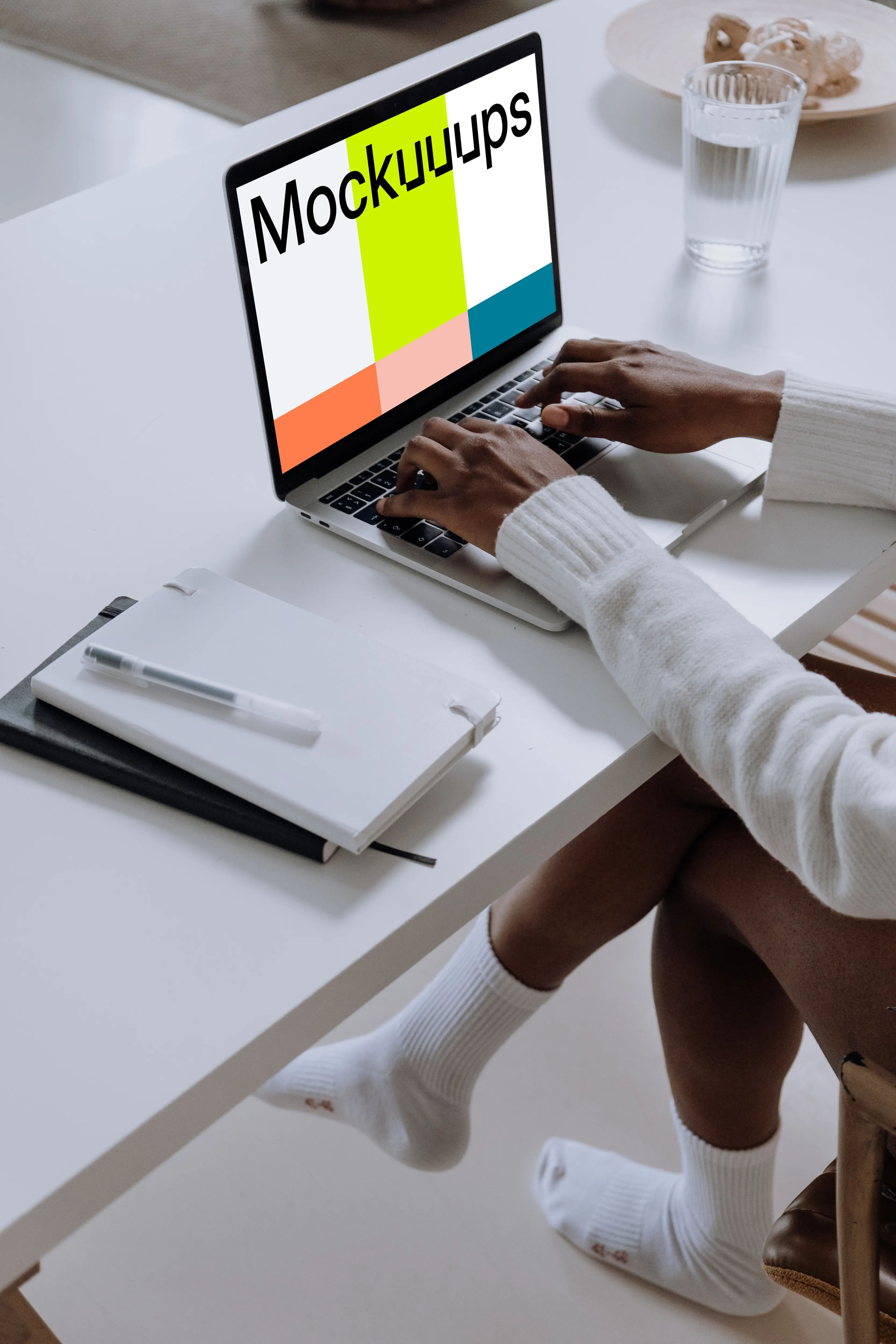 MacBook Pro Mockup on a white table with a notebook and cup of water