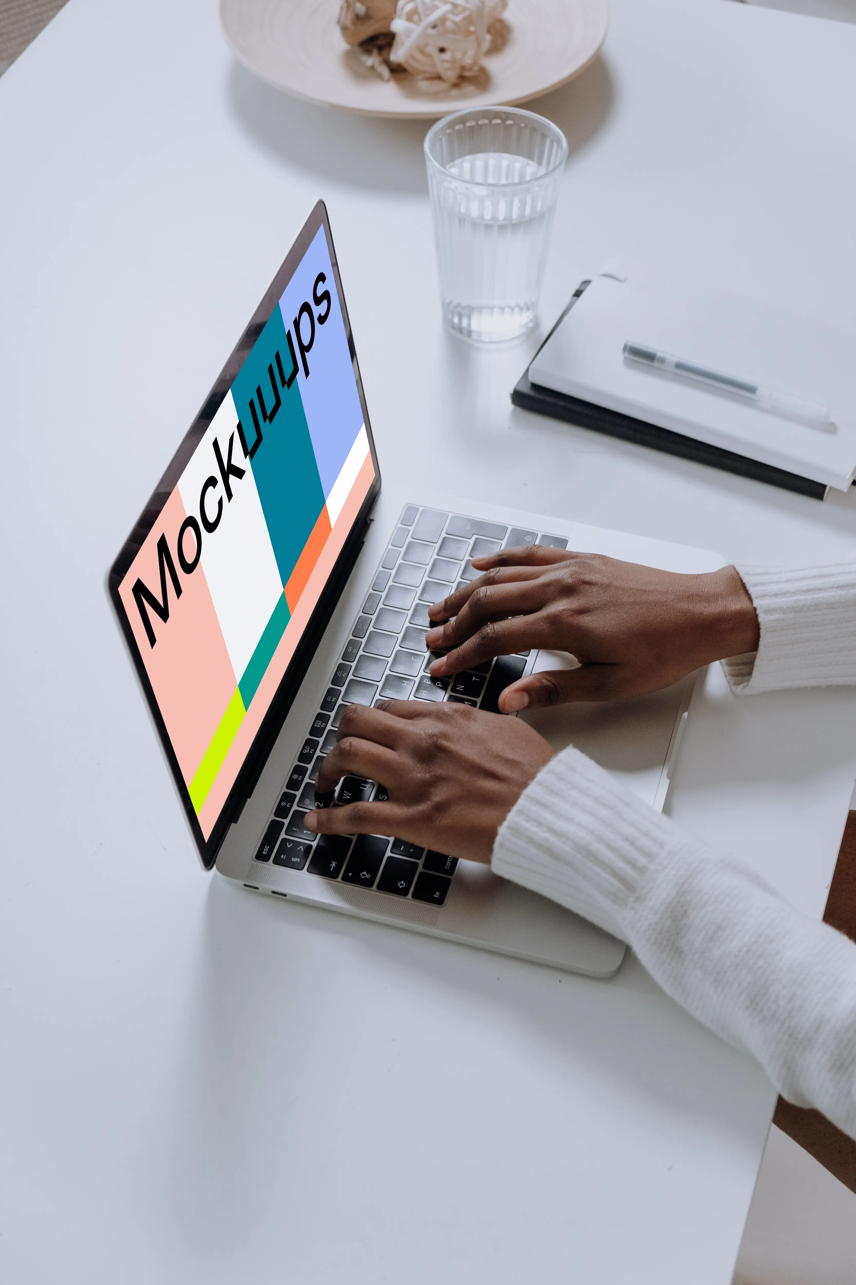 MacBook Pro mockup on a white table with glass of water at the side