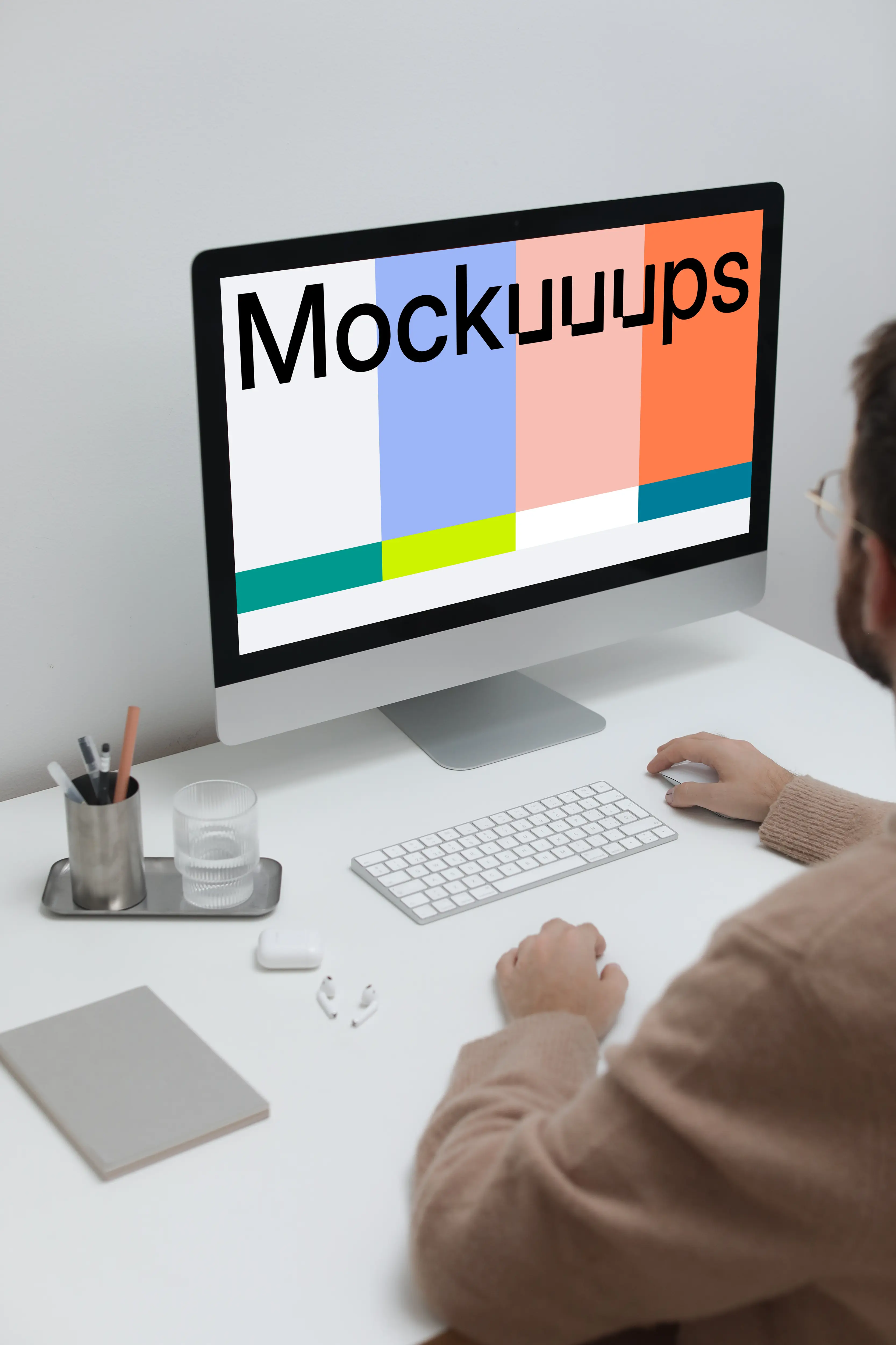 Man working on his iMac on a white table mockup
