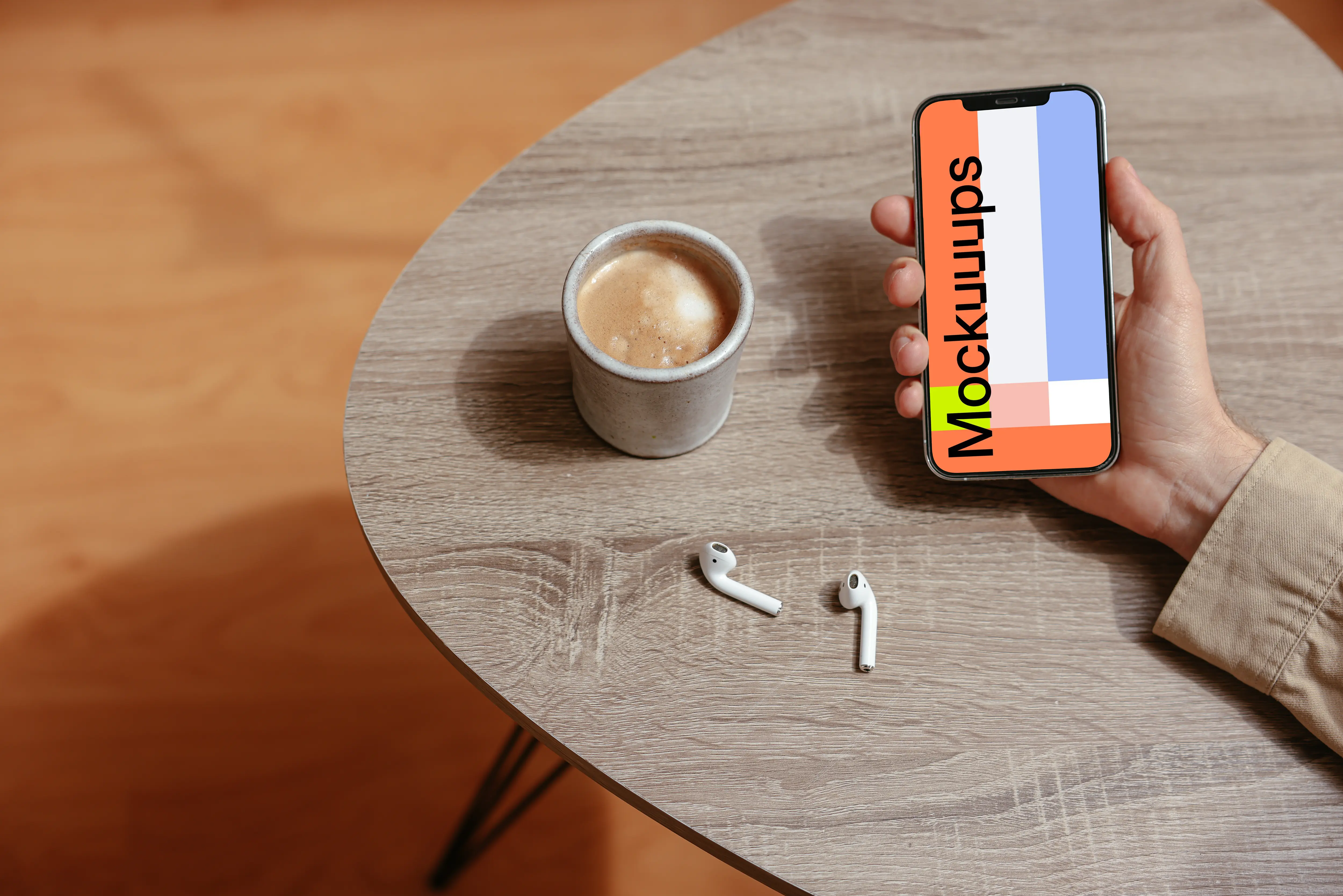 Simple handheld iPhone mockup held on the table with a pair of Airpods at the side