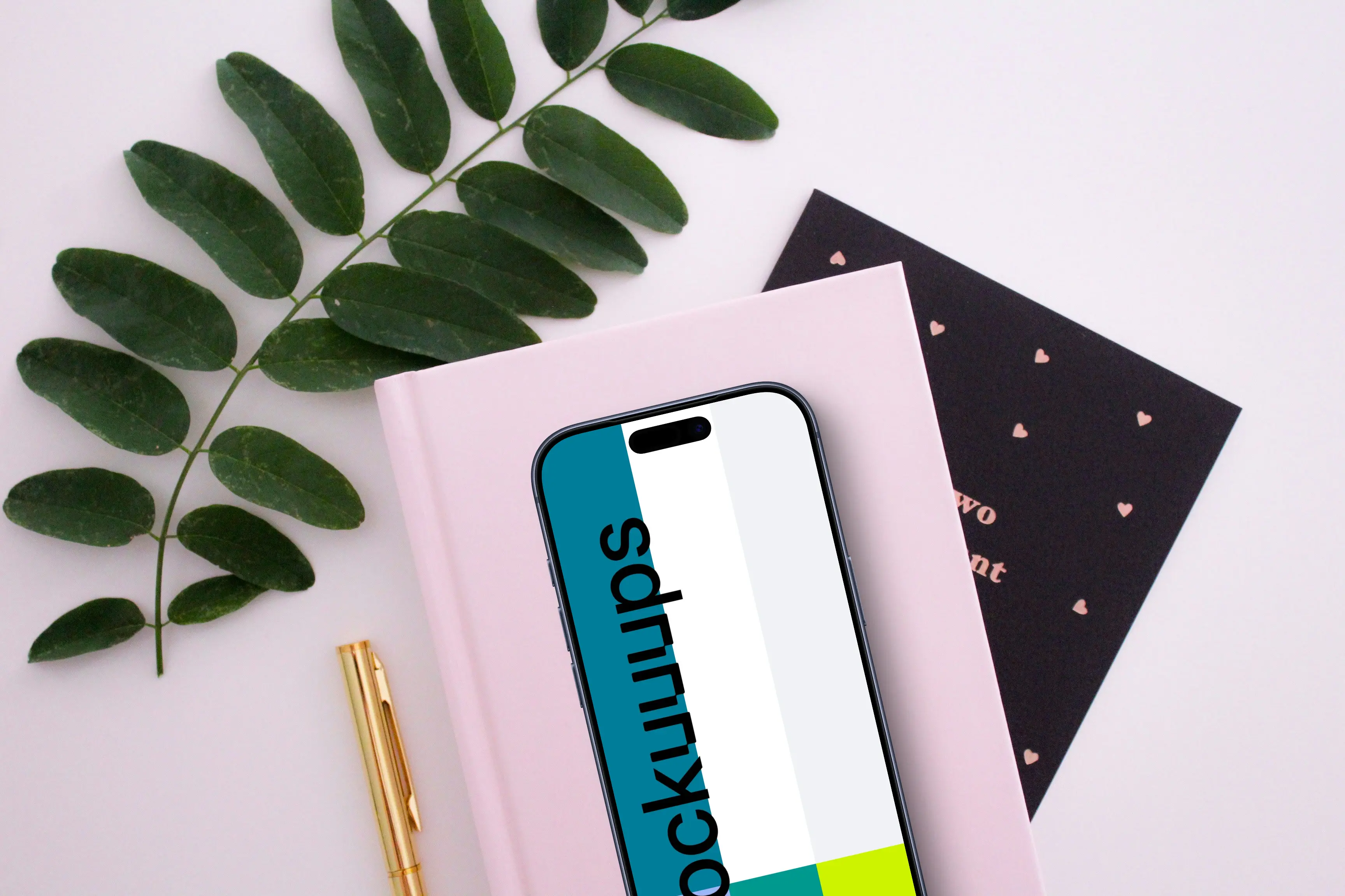 Smartphone mockup on a pink book with green leaves around