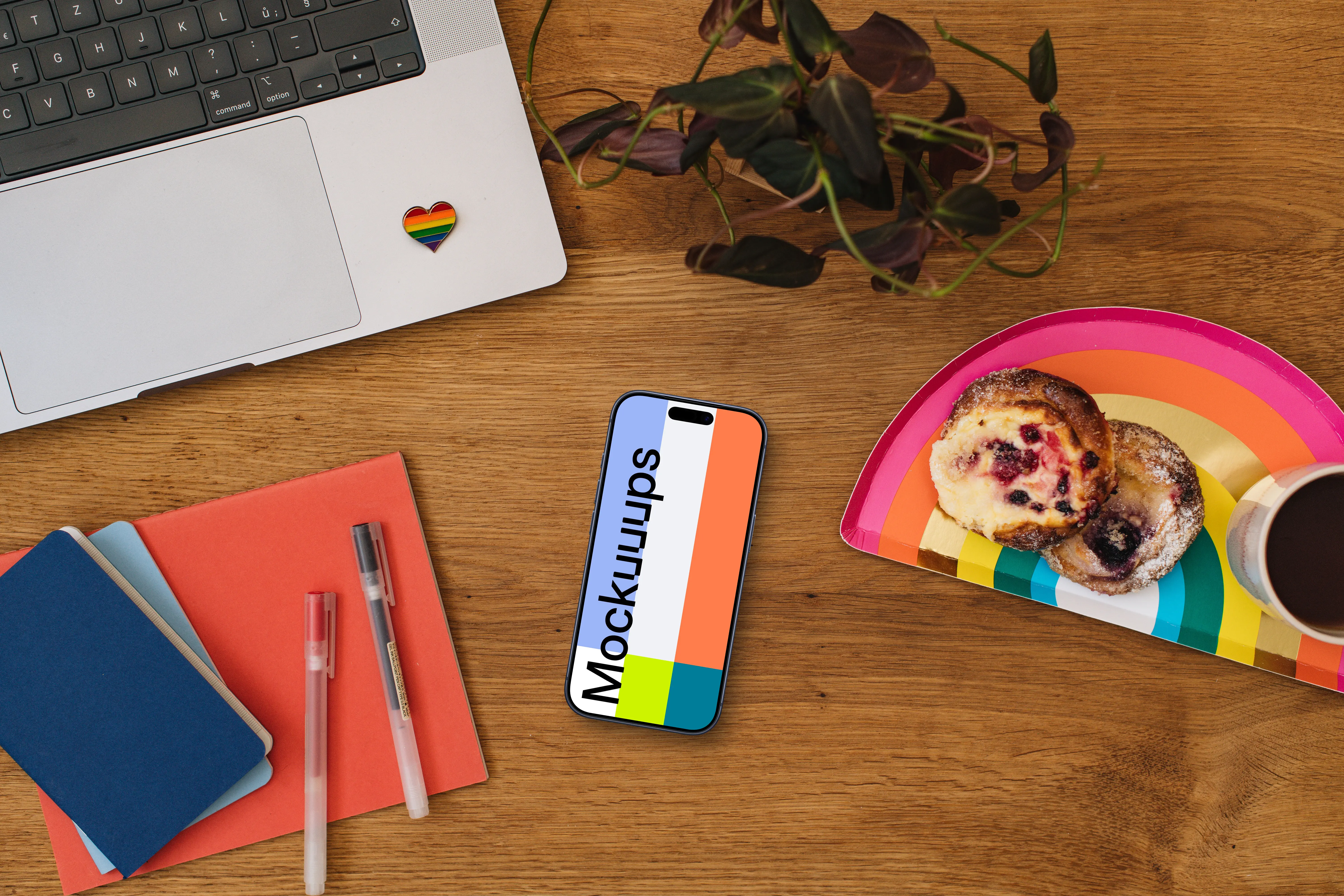 Smartphone mockup on a wooden table next to the rainbow tray with cakes
