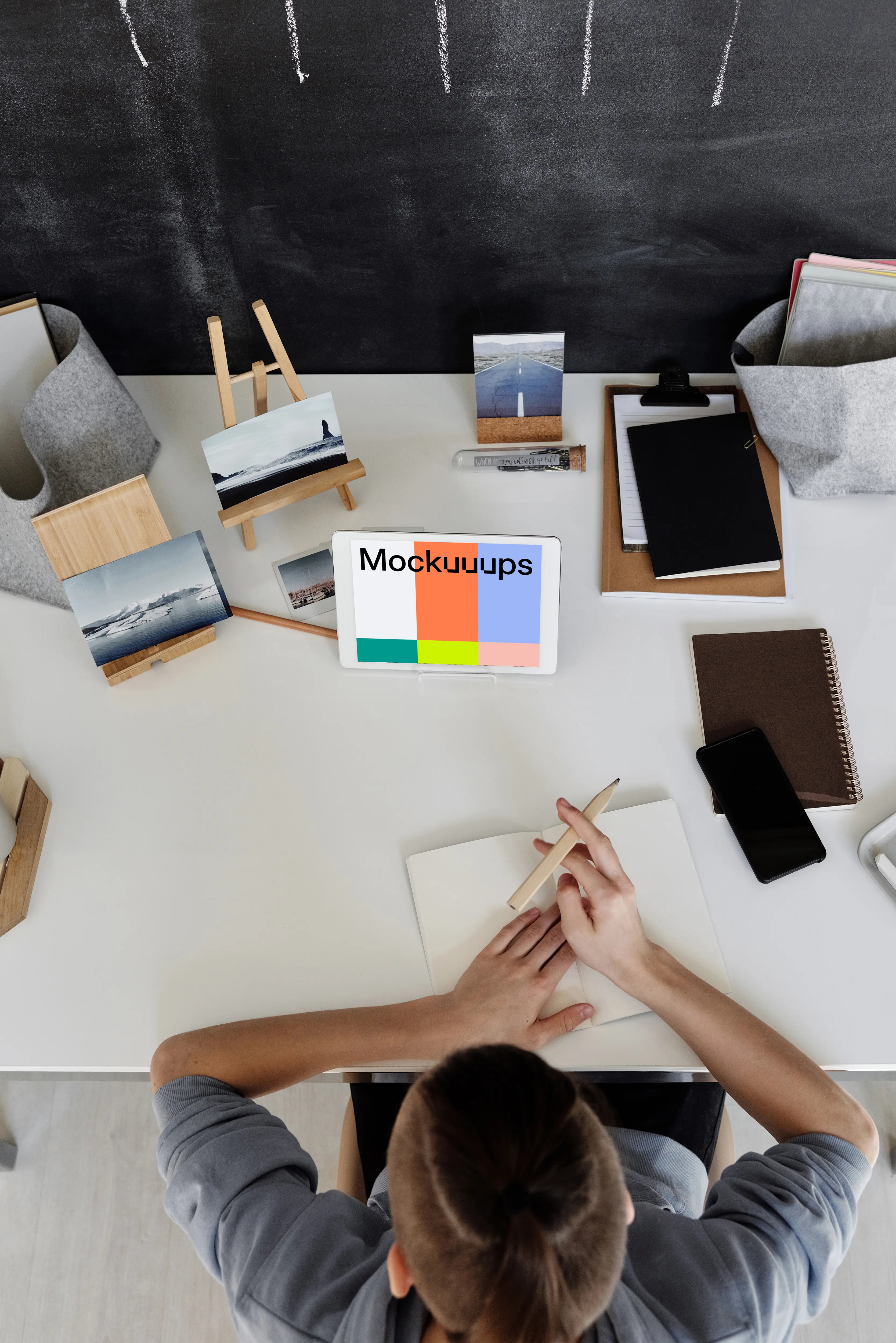 Young boy using an iPad mini on a table with a jotter by the side mockup