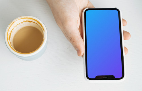 iPhone mockup in a user’s hand with a cup of coffee at the side