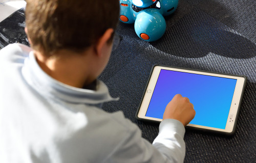 Kid using an iPad mockup with a toy by the side