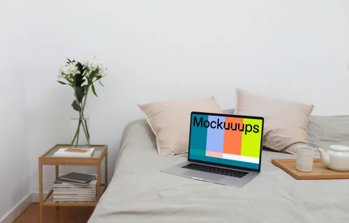 MacBook mockup on a bed with tea set by the side