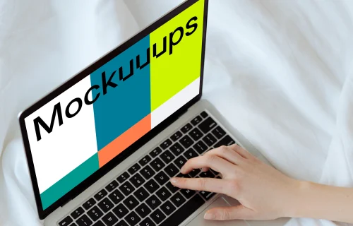 MacBook mockup on a white bed with a user typing on the laptop