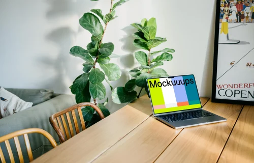 MacBook Pro mockup on a dining table beside a photo frame