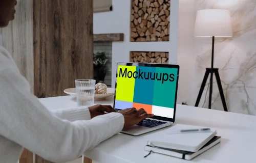 MacBook Pro mockup on white table with notebook by the side