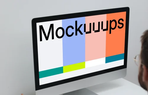 Man working on his iMac on a white table mockup