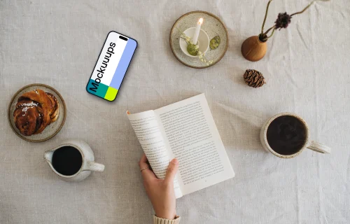 Top view of woman reading a book with smartphone on the side