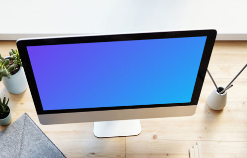 Young girl holding a pencil and using her iMac mockup