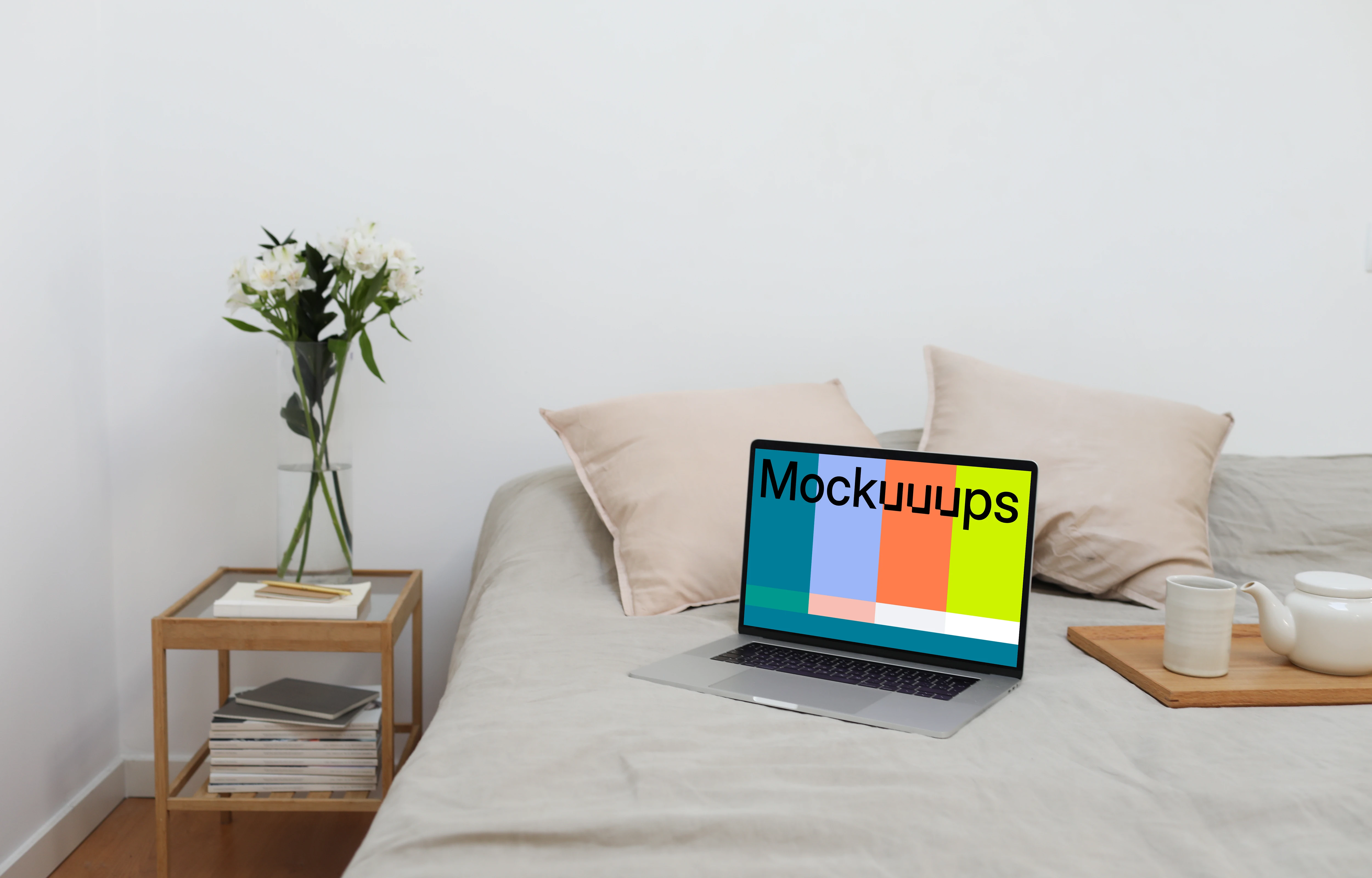 MacBook mockup on a bed with tea set by the side