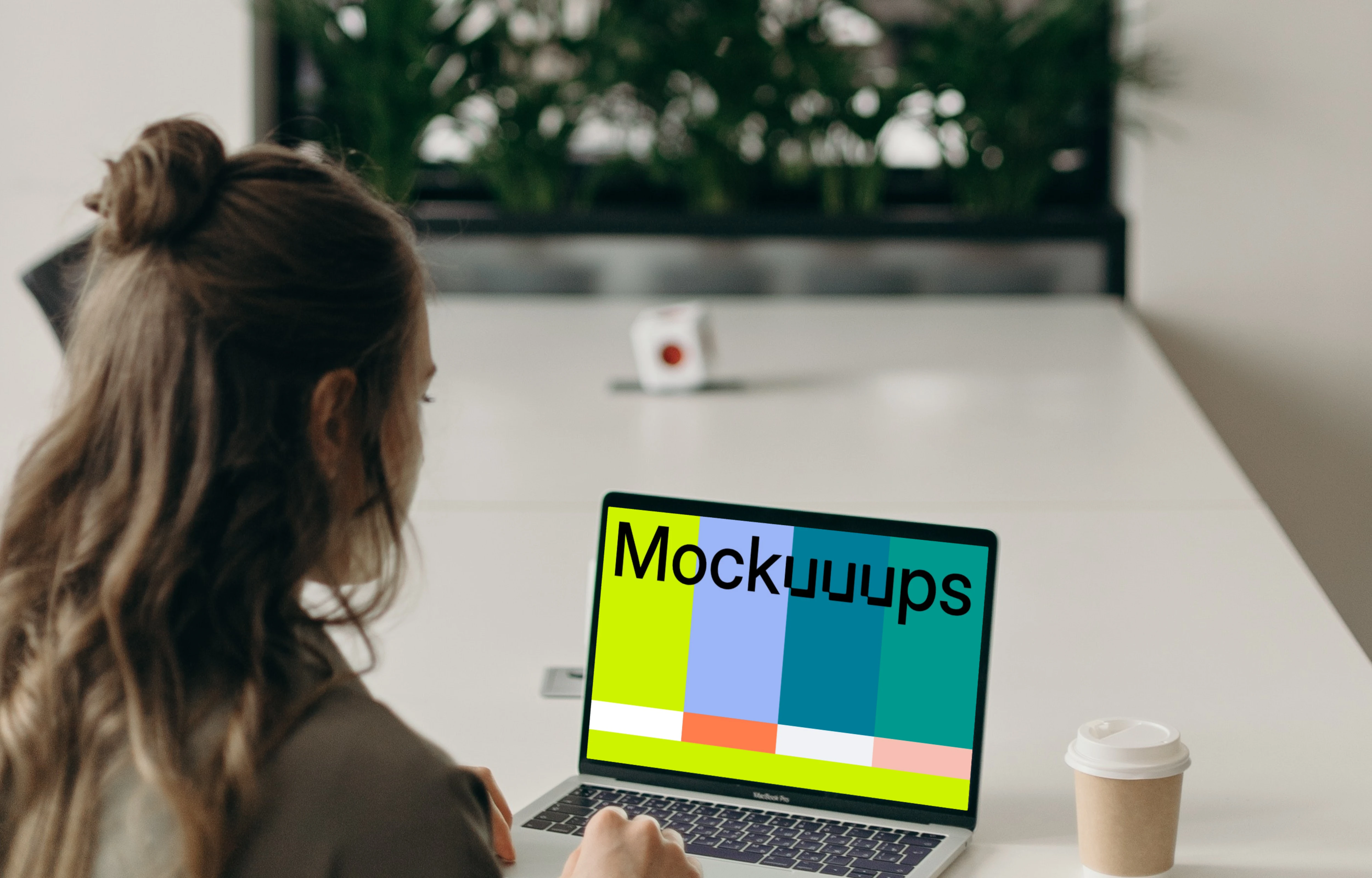 MacBook Pro mockup on a white table in use by a woman