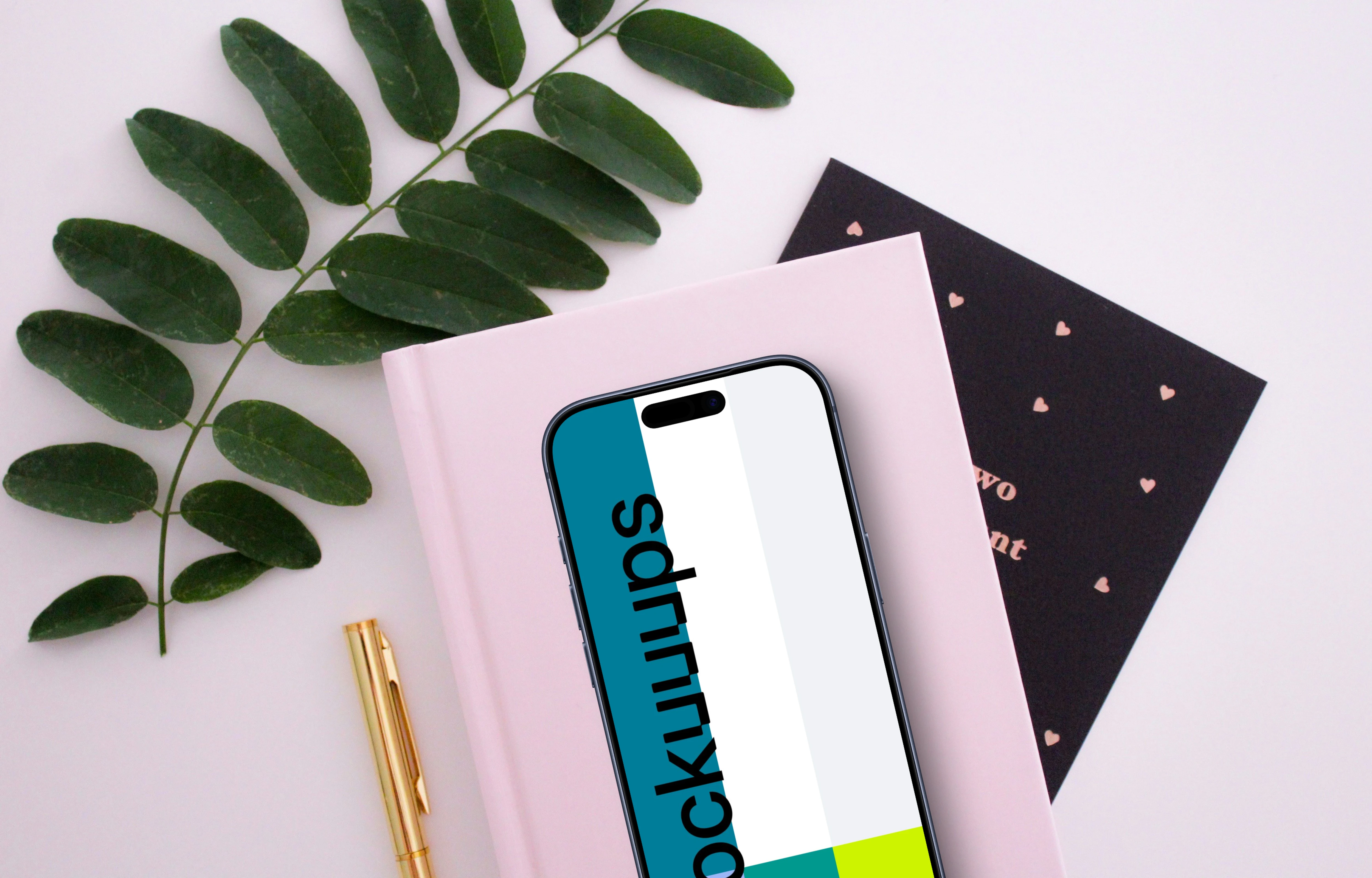 Smartphone mockup on a pink book with green leaves around