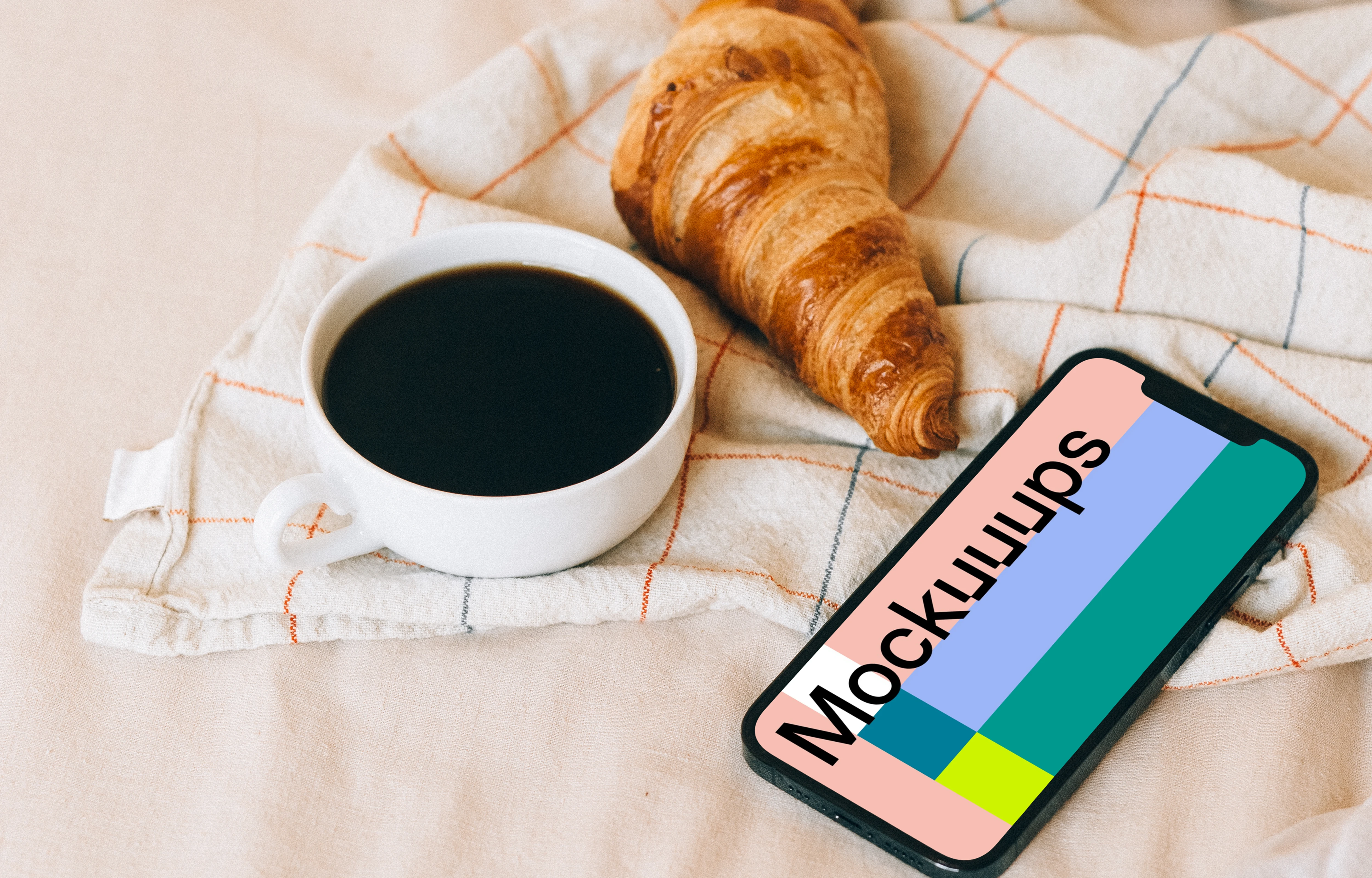 iPhone 12 Pro mockup beside a croissant and a cup of coffee