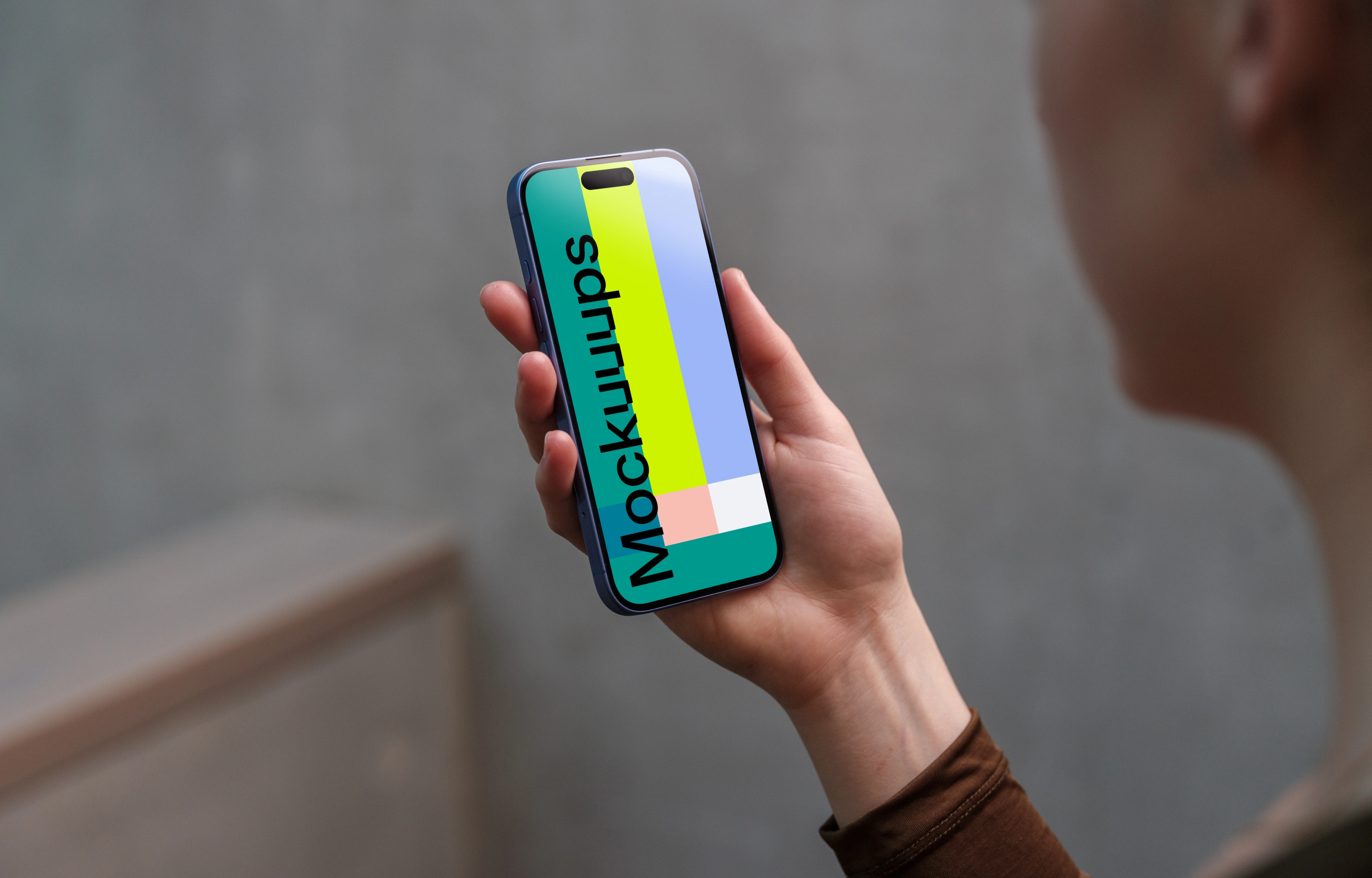iPhone 16 mockup in a woman's hand with concrete backdrop