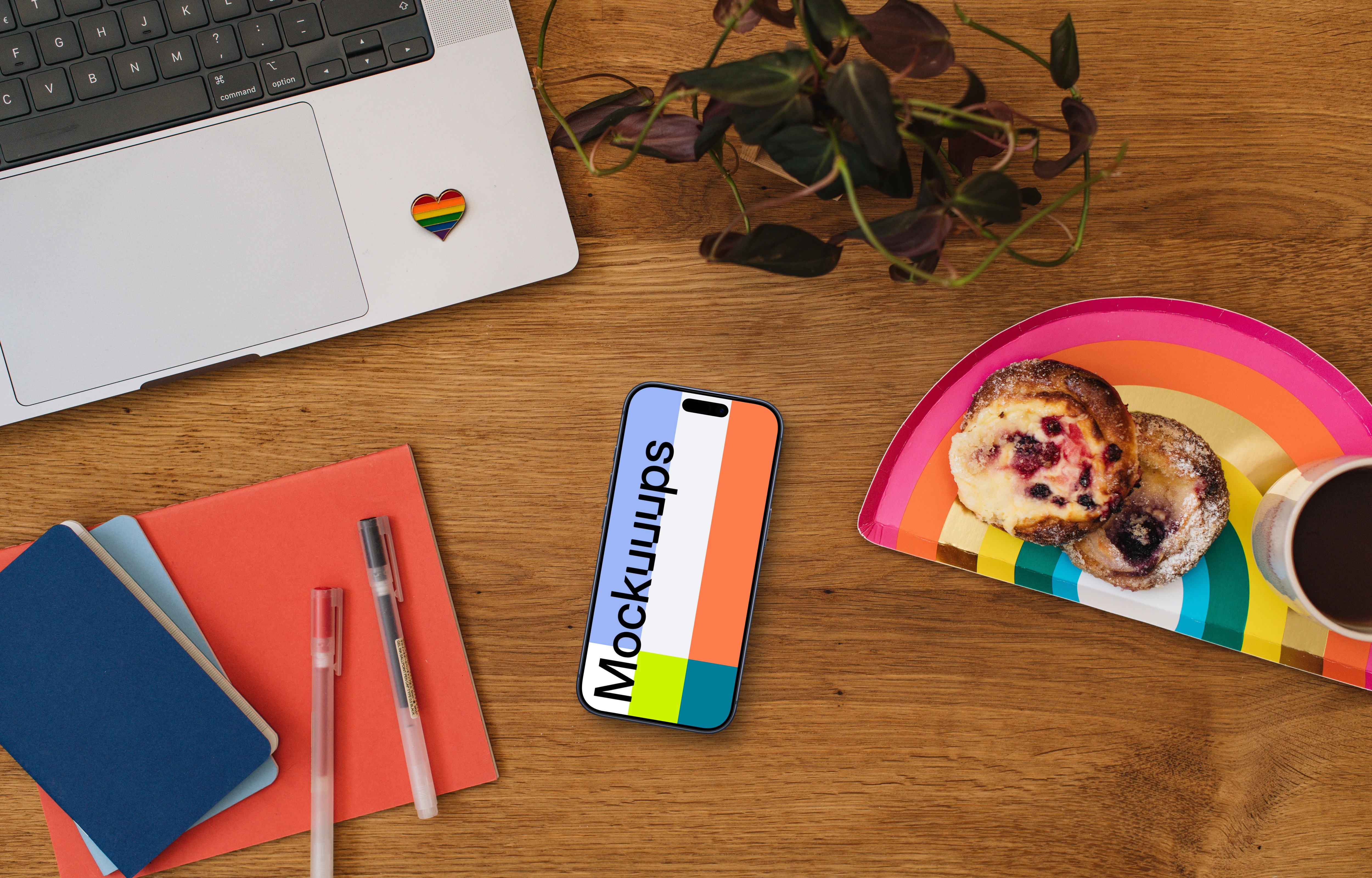 Smartphone mockup on a wooden table next to the rainbow tray with cakes