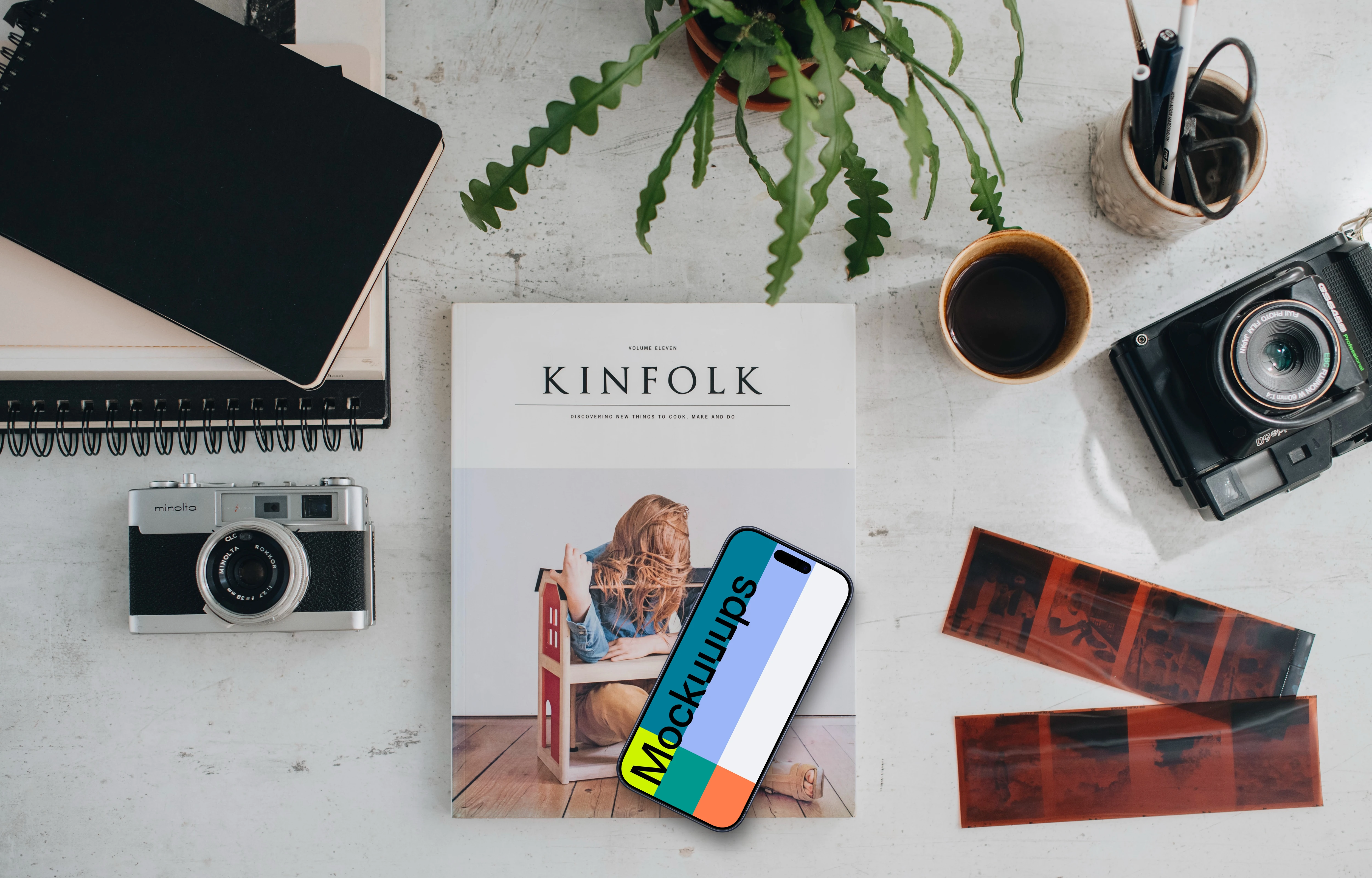 Top view of phone mockup surrounded by analog cameras and negatives