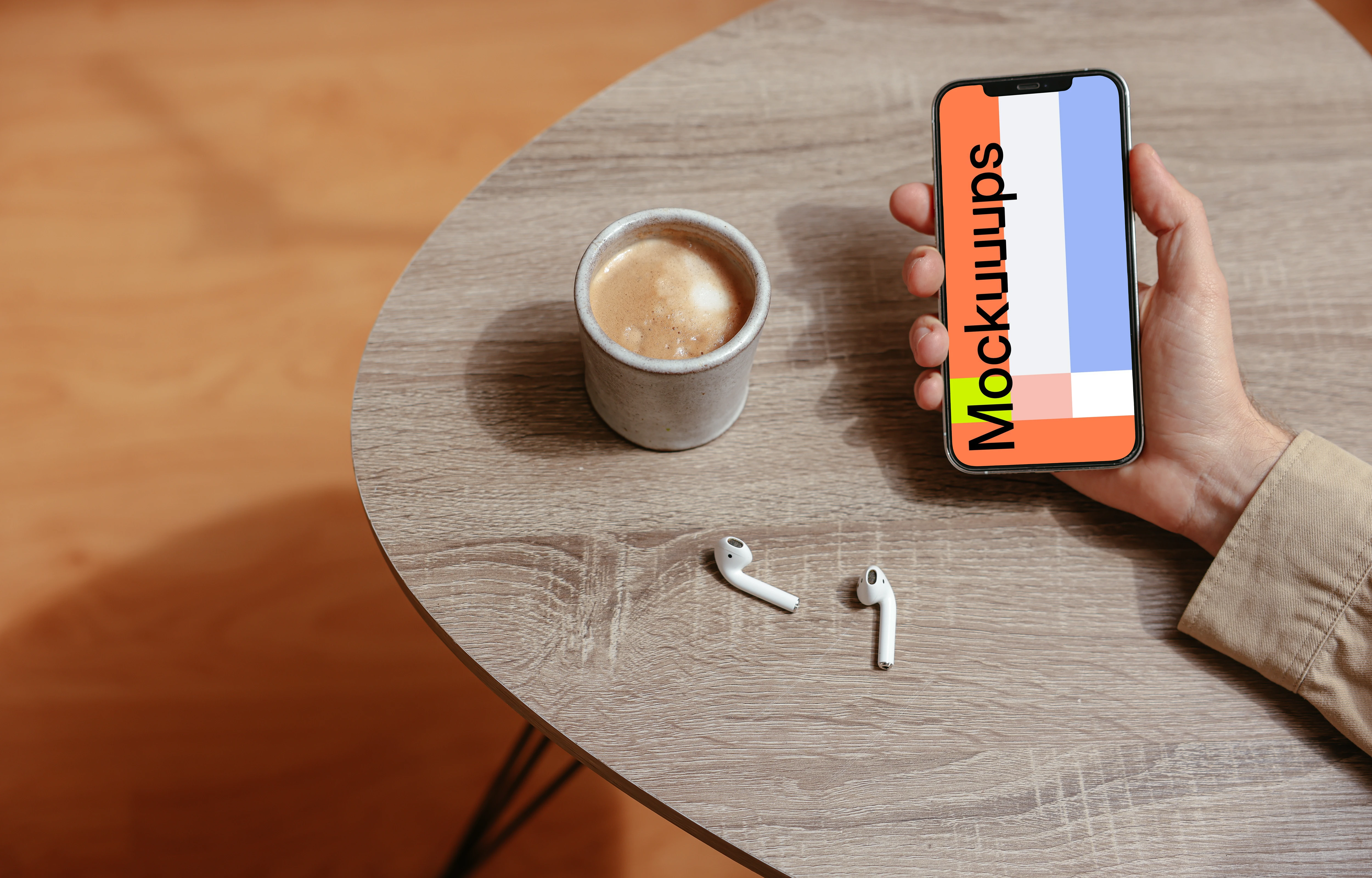 Simple handheld iPhone mockup held on the table with a pair of Airpods at the side