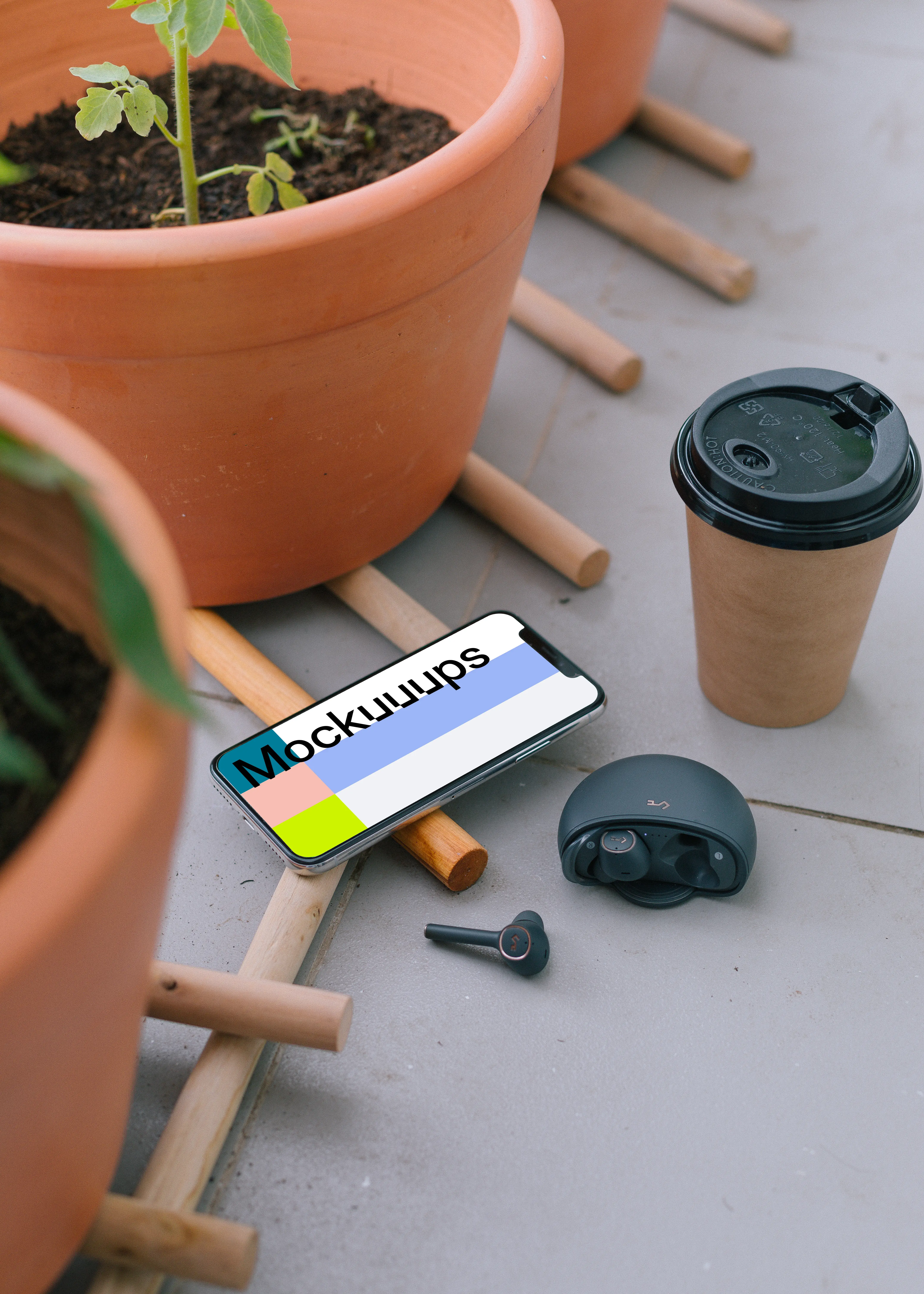  iPhone 12 mockup beside to a cup of coffee and earbuds