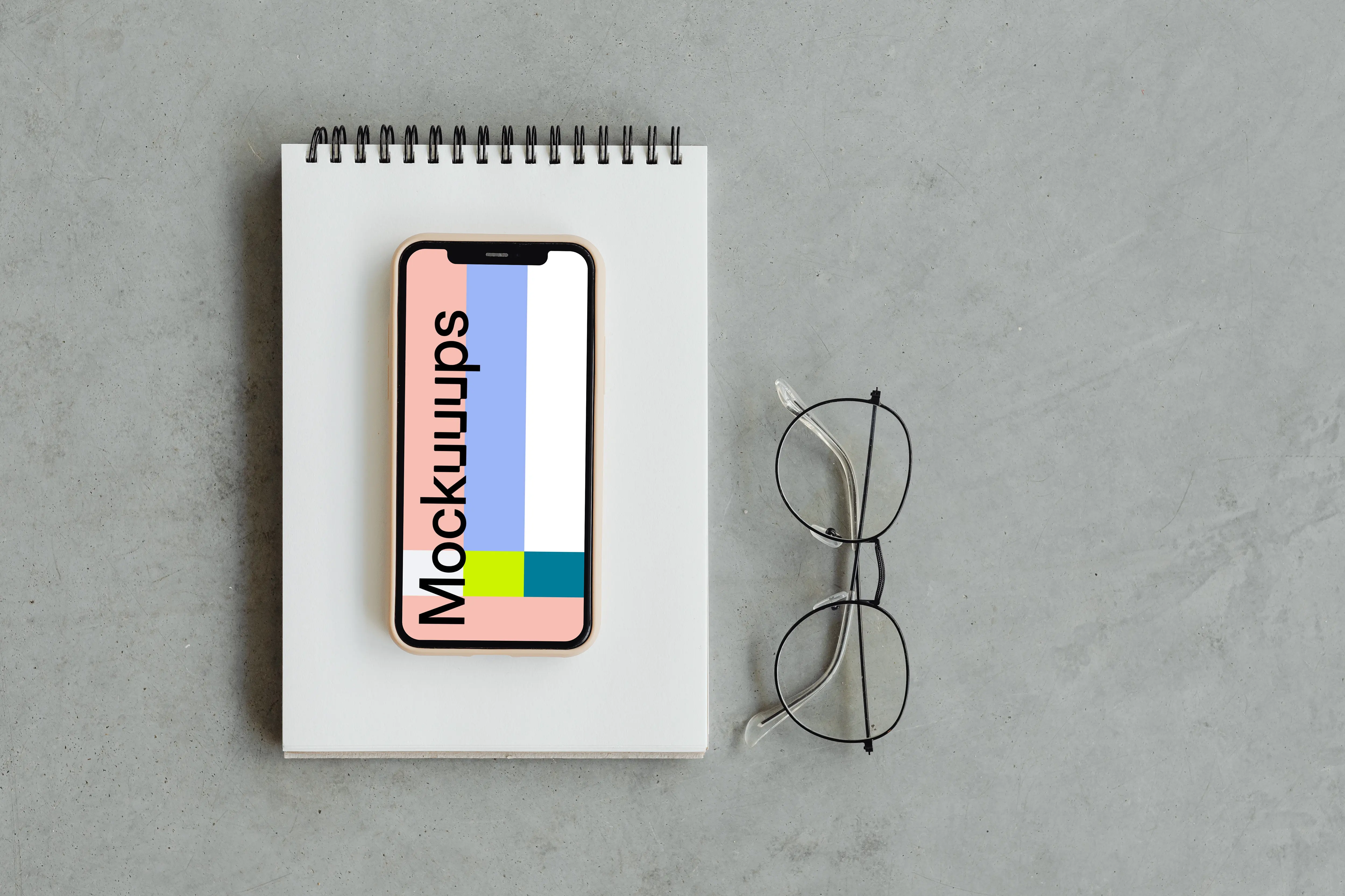 iPhone mockup on a jotter with reading glasses by the side.
