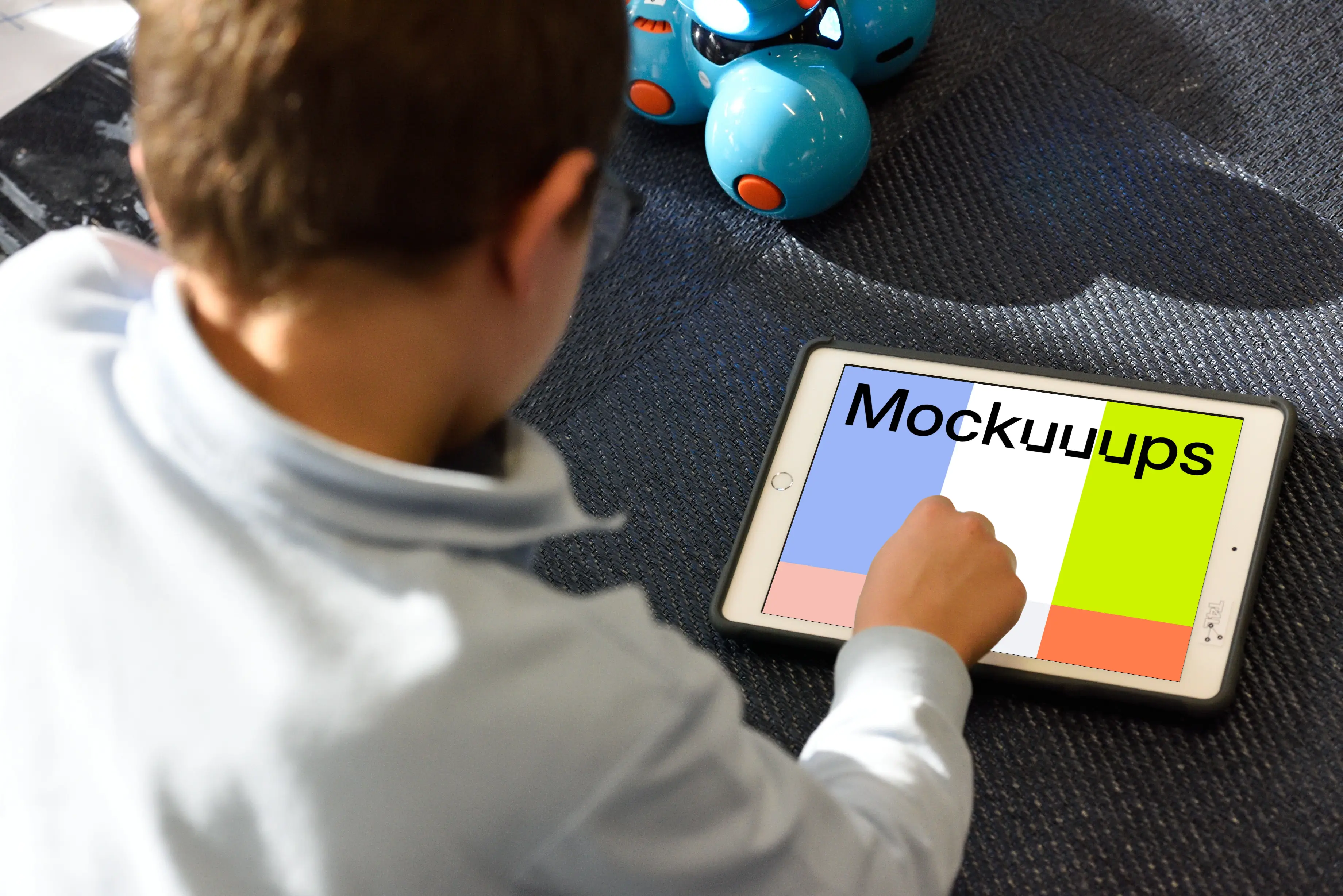 Kid using an iPad mockup with a toy by the side