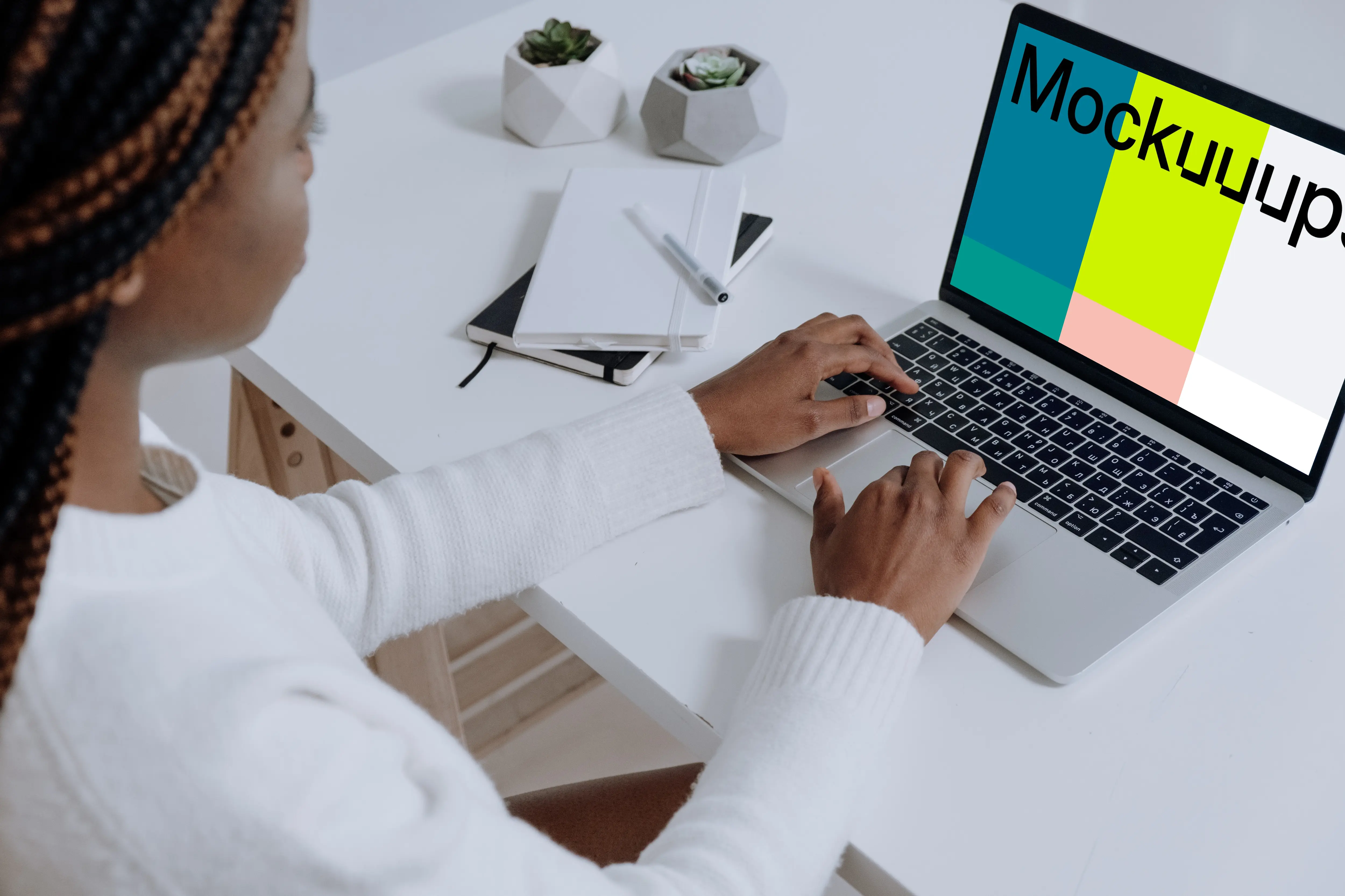 MacBook Pro on white table beside a notebook and pen