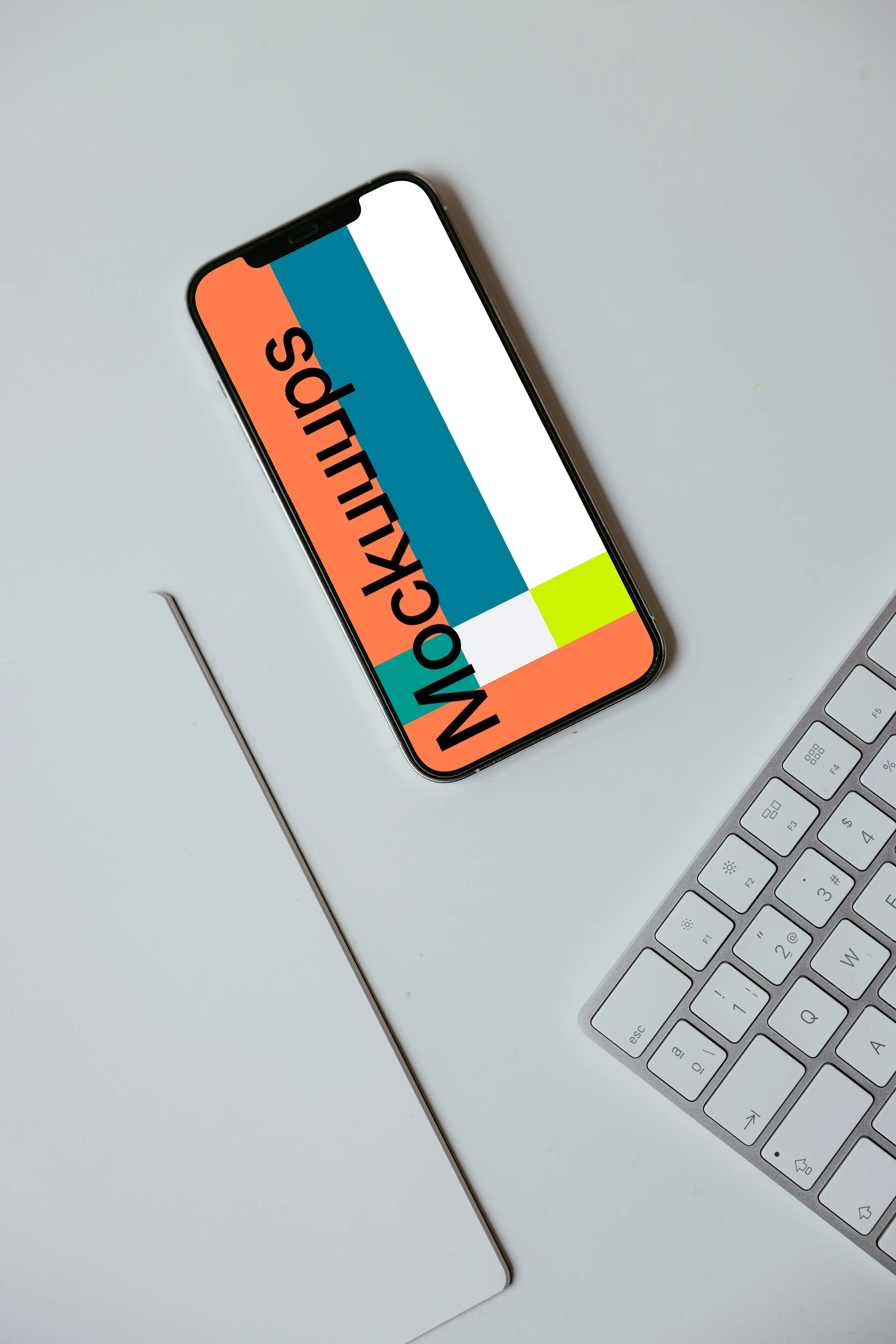 Minimal iPhone mockup on a white table with a wireless keyboard by the side